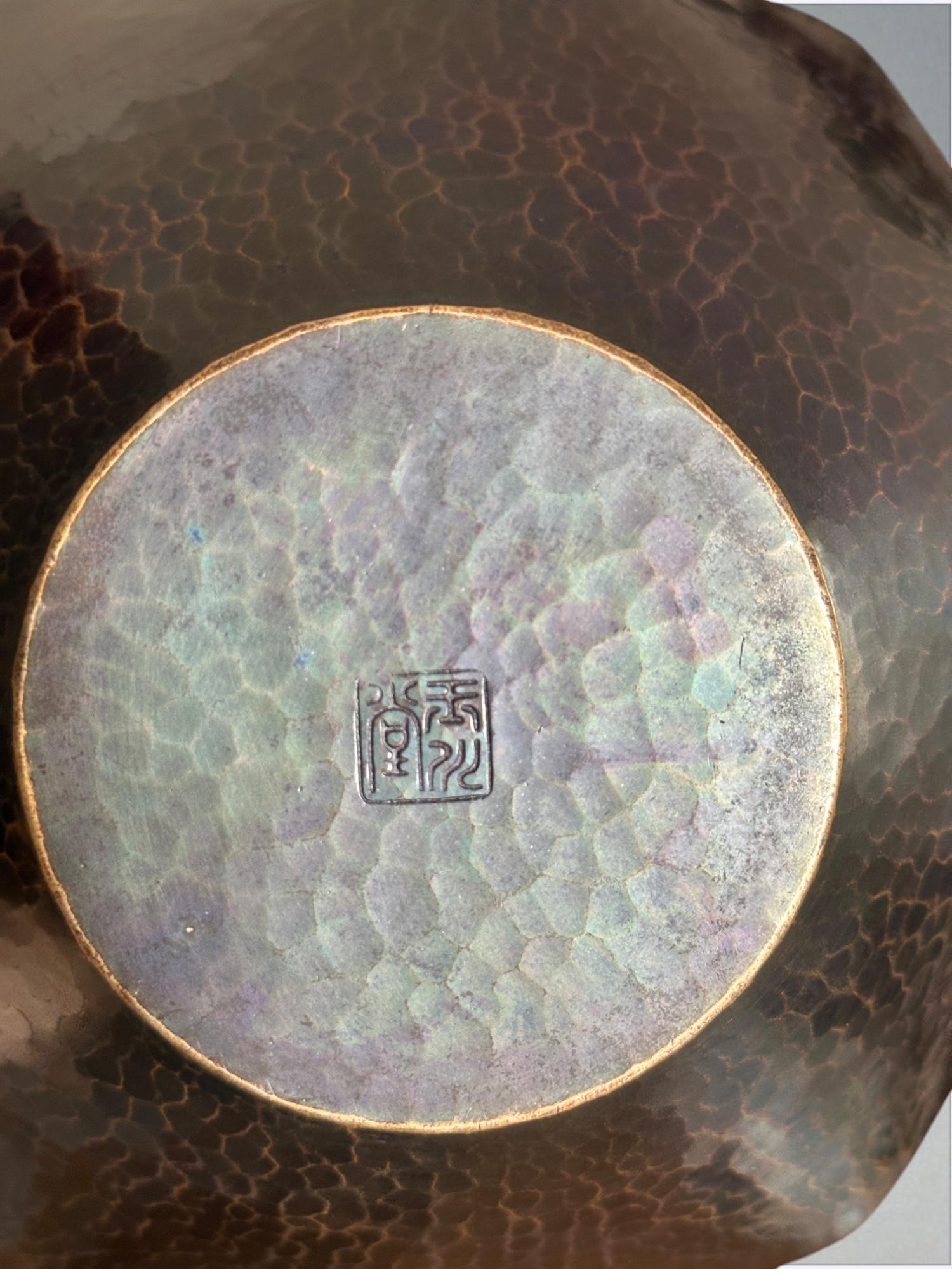 Magnifico esempio di arte metallurgica giapponese, questo vaso di rame martellato a mano è stato creato dal rinomato laboratorio Gyokusendō (玉川堂), noto per aver preservato le tecniche secolari di tsuiki (鎚起), un metodo tradizionale per modellare il