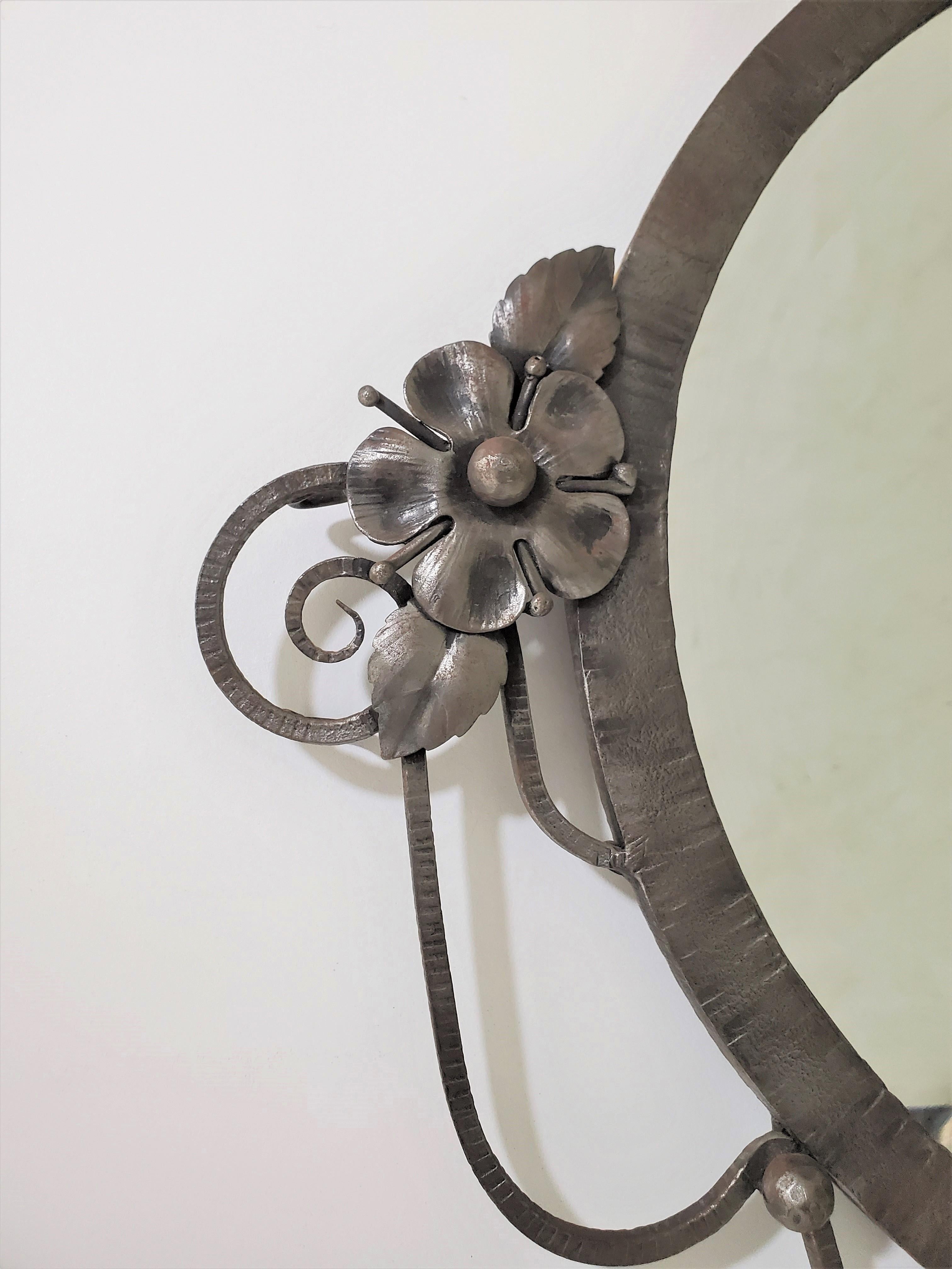 Belgian Art Moderne/ Modernist oval mirror in hand forged nickeled iron with decorative swag openwork design, small rosettes, leafage and scroll ends flanking sides and center with wide beveled mirror inset.

 Can be used with Contemporary design,