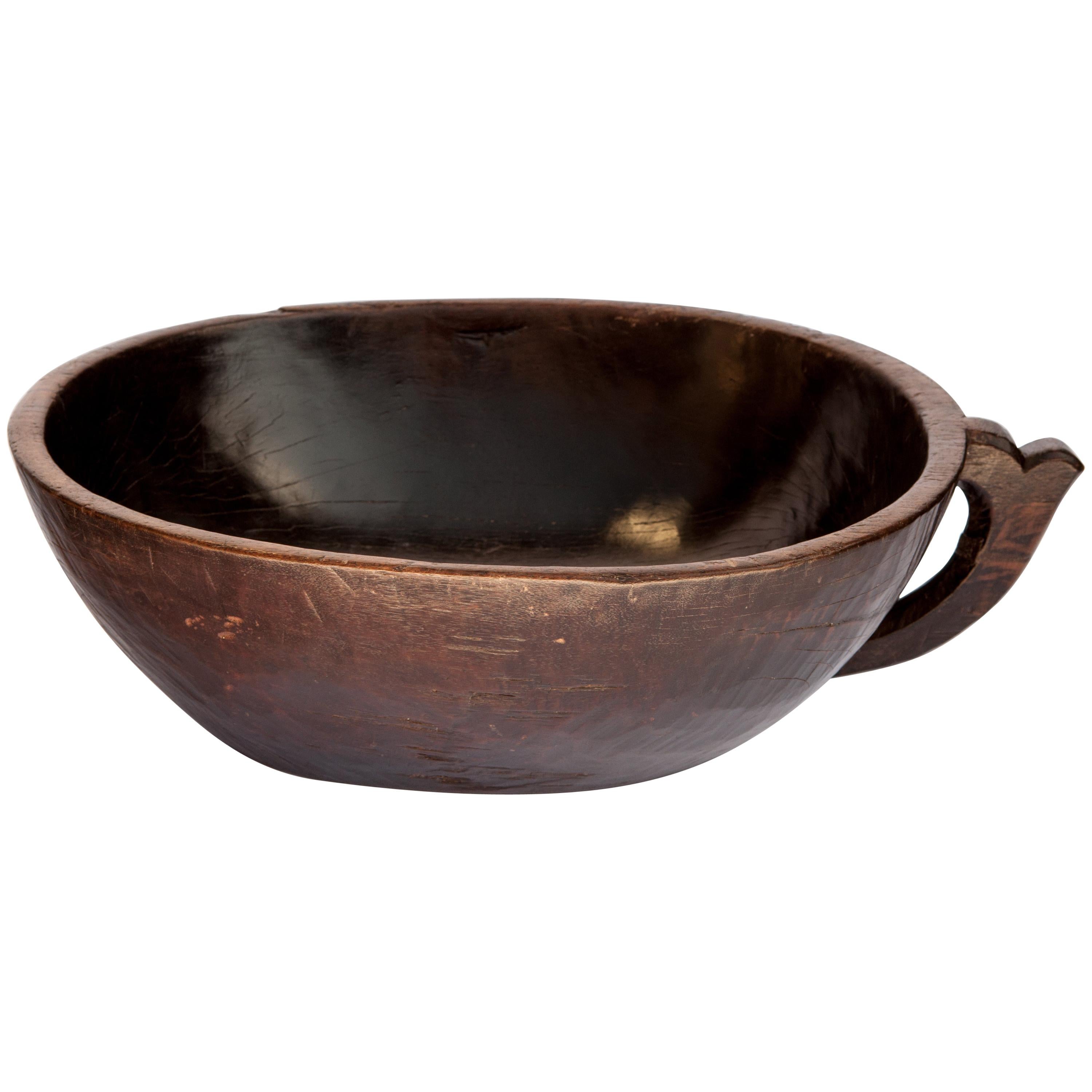Vintage hand hewn wooden bowl with handle from Sulawesi, Indonesia, mid-20th century.
This wooden bowl from the mountains of Sulawesi was fashioned by hand from a single piece of wood. The pronounced oblong shape of this piece is somewhat unusual.