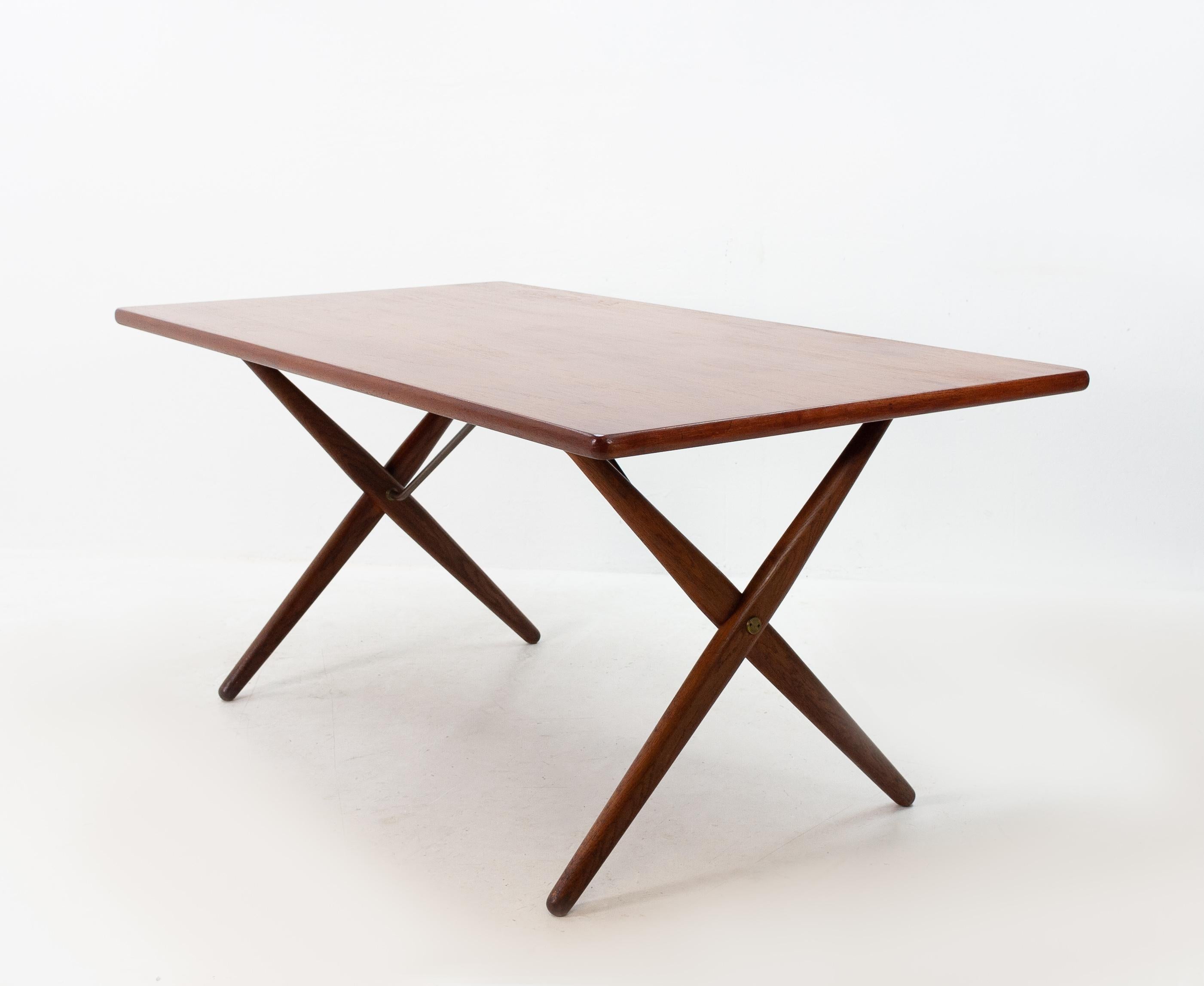 Iconic dining table model AT-303, in teak, oak and brass, by Hans J. Wegner for Andreas Tuck, Denmark, 1955. Dining table with X-shaped legs, by Danish Designer Hans Wegner. This table is considered as one of the best known designs from Wenger.