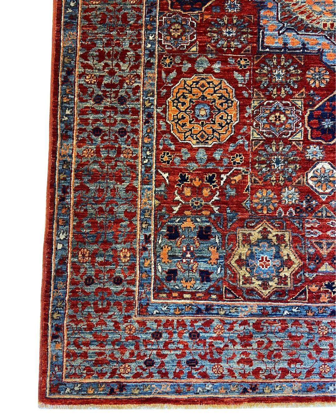 Ce tapis afghan 4' x 6' noué à la main avec un motif de médaillon en laine rouge et indigo incarne l'héritage profond et l'élégance durable du tissage traditionnel. En son cœur se trouve un médaillon central saisissant, symétriquement encadré par un