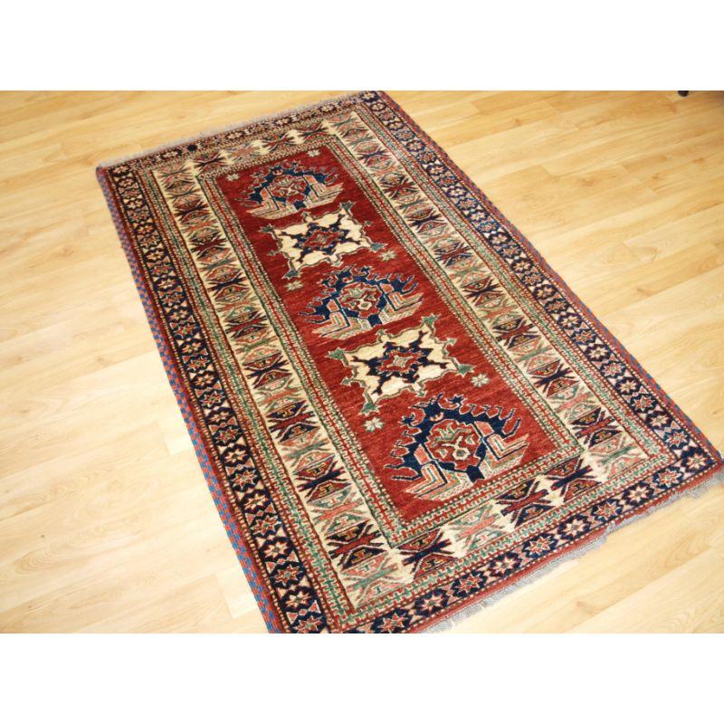 Hand knotted Afghan rug with traditional Caucasian Kazak design.

Pleasing 19th century design with five small medallions on an attractive soft rust red coloured back ground. The border design is a classic Caucasian 19th century design.

The rug