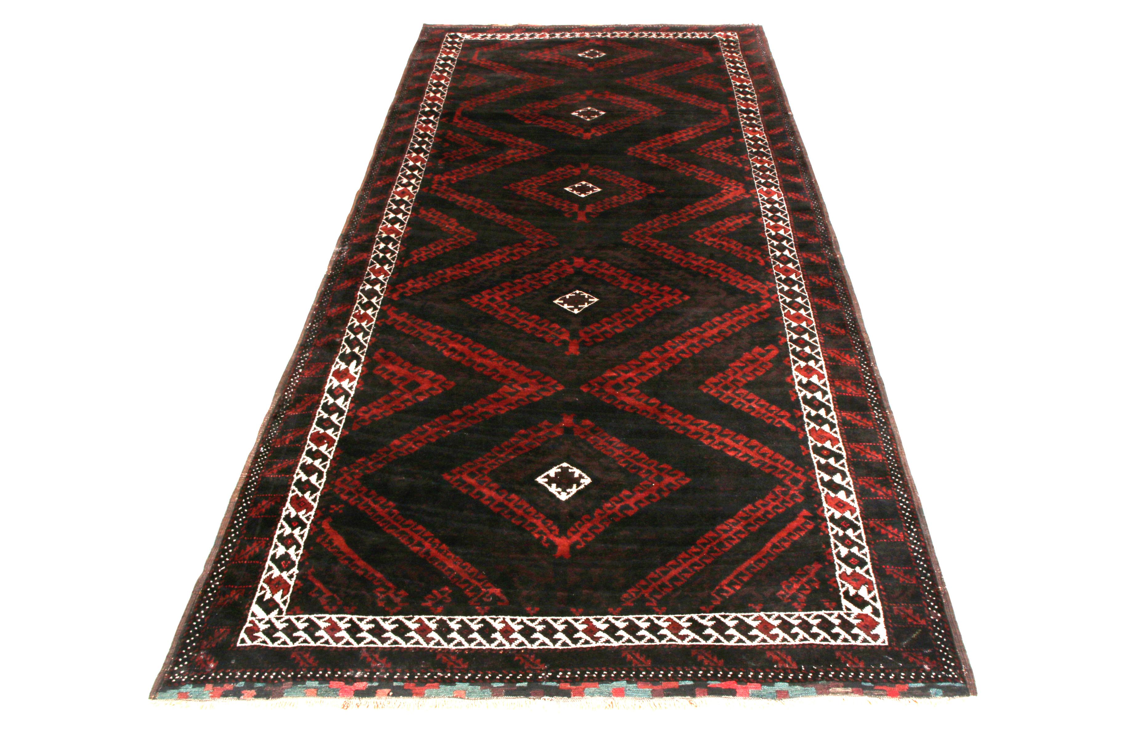 Hand knotted in wool originating circa 1950-1950, this 4x9 mid-century rug is a vintage Persian rug hailing from the Baluch rug weavers of renown, with this particular item employing an notably rich, dark brown colorway reading almost black against