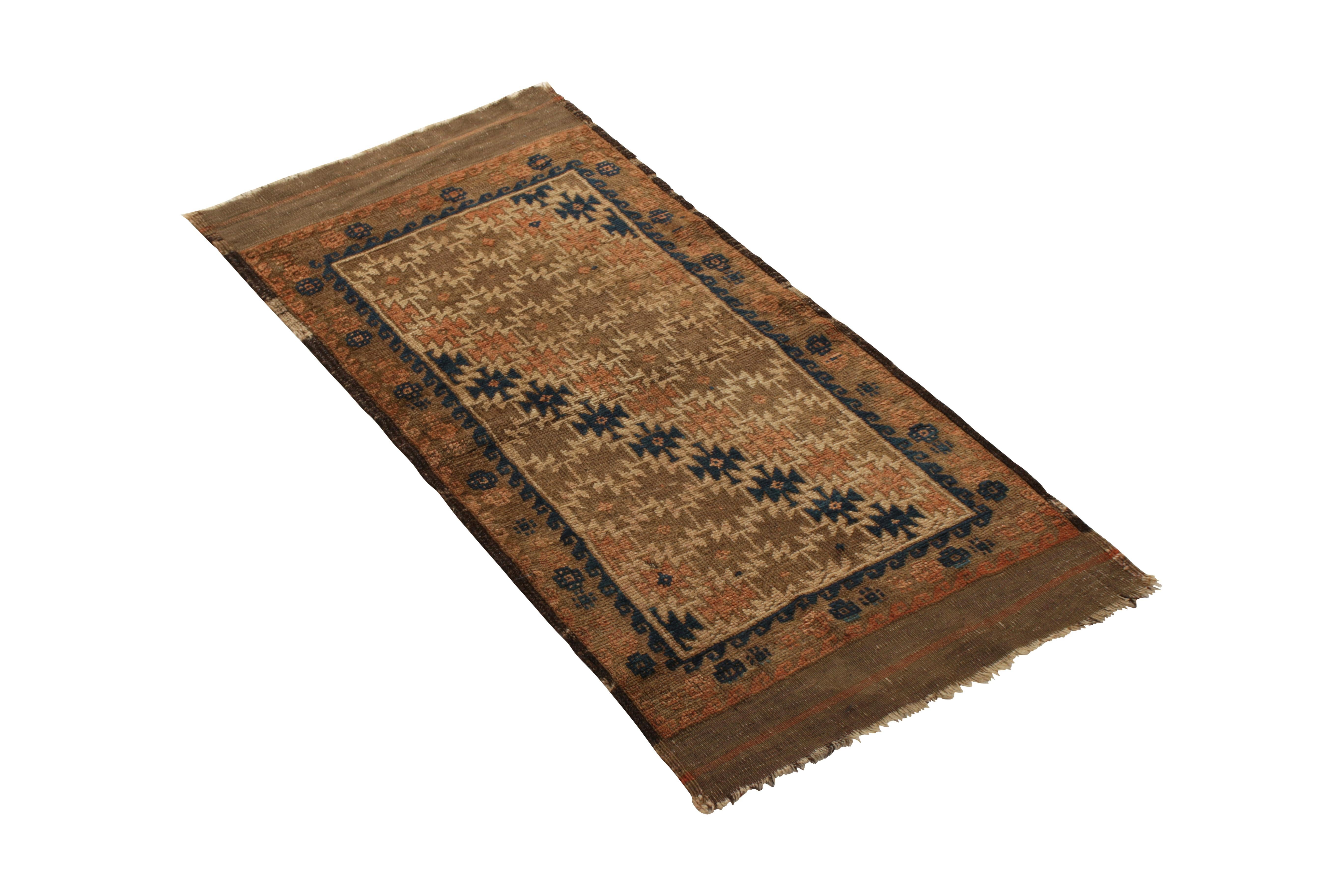 Hand knotted in wool originating circa 1890-1900, this 1 x 2 antique rug denotes a rare Baluch rug design in both an uncommon, versatile accent rug size and a rich play of beige-brown with navy blue and orange accents. Enjoying only mild wear