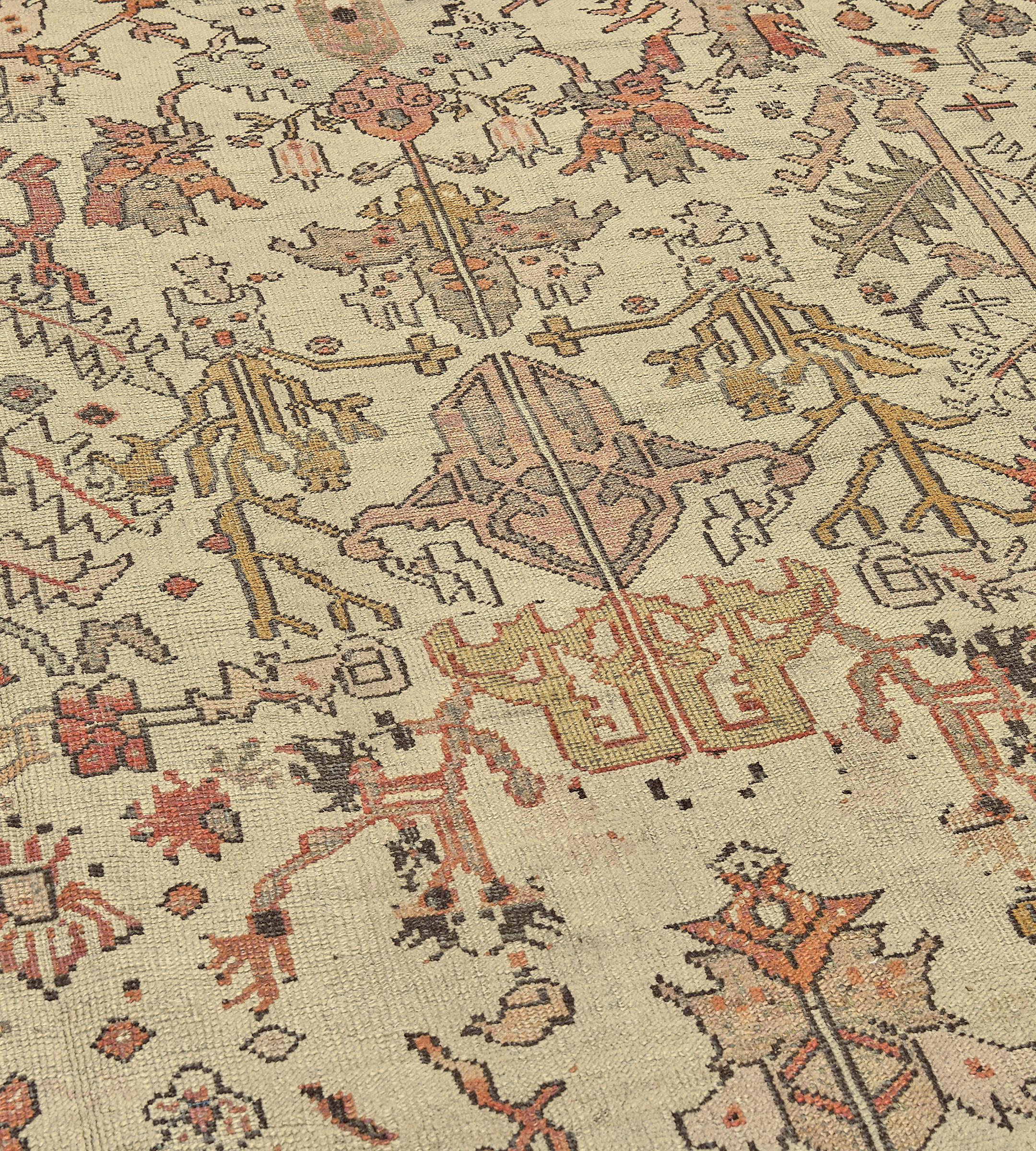 Cet ancien tapis de Ghordes, datant de 1880, présente un champ ivoire avec un motif général de palmettes angulaires brun caramel, rouge terre cuite et brun taupe et de feuilles de vigne dentelées angulaires, dans une large bordure brun taupe de