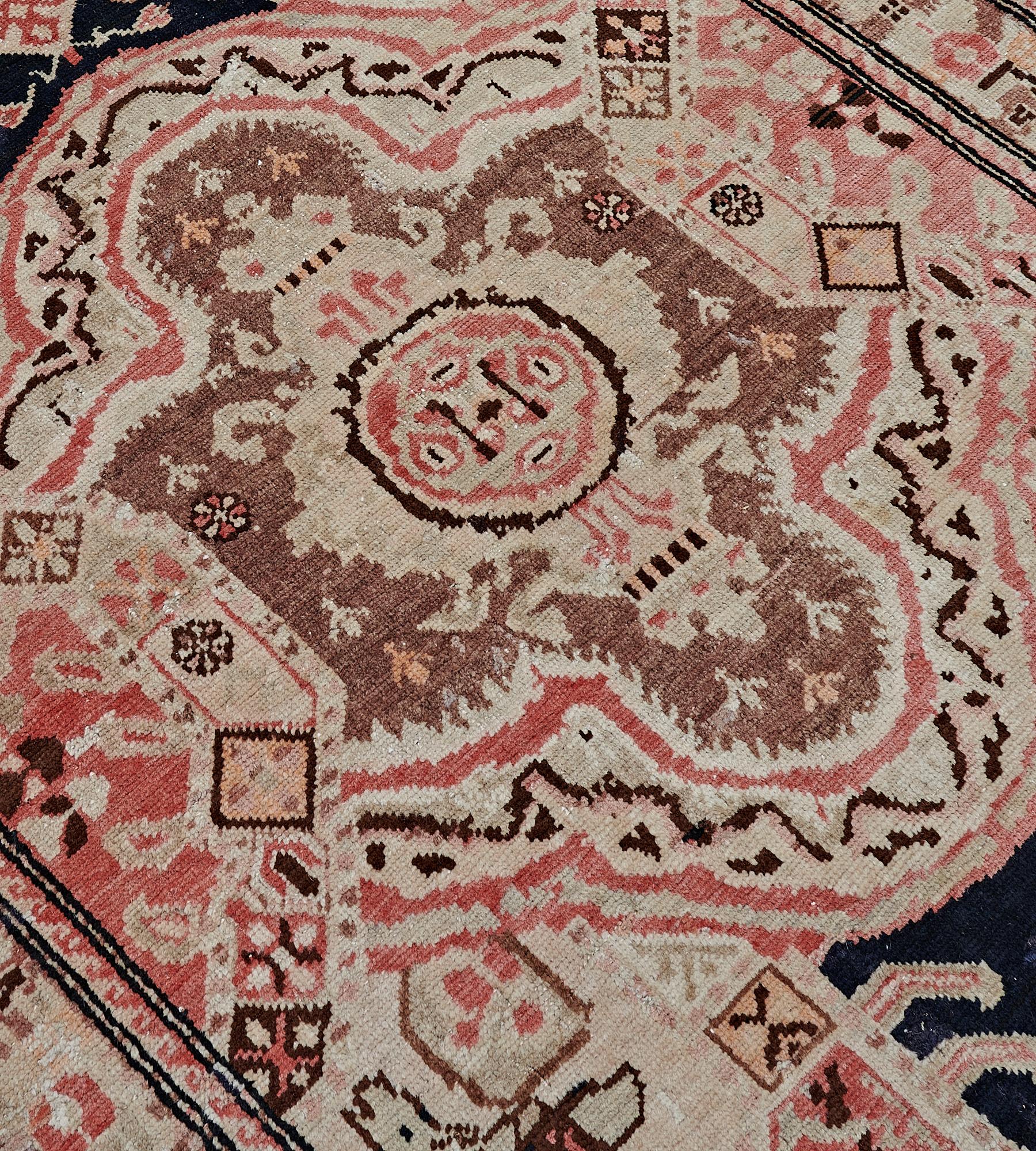 This antique, circa 1900, Karabagh runner has a charcoal-blue field with a central column of ivory and brick-red cusped lozenges alternating with fox-brown lozenges each containing a central rosette surrounded by floral motifs, flanked at each side