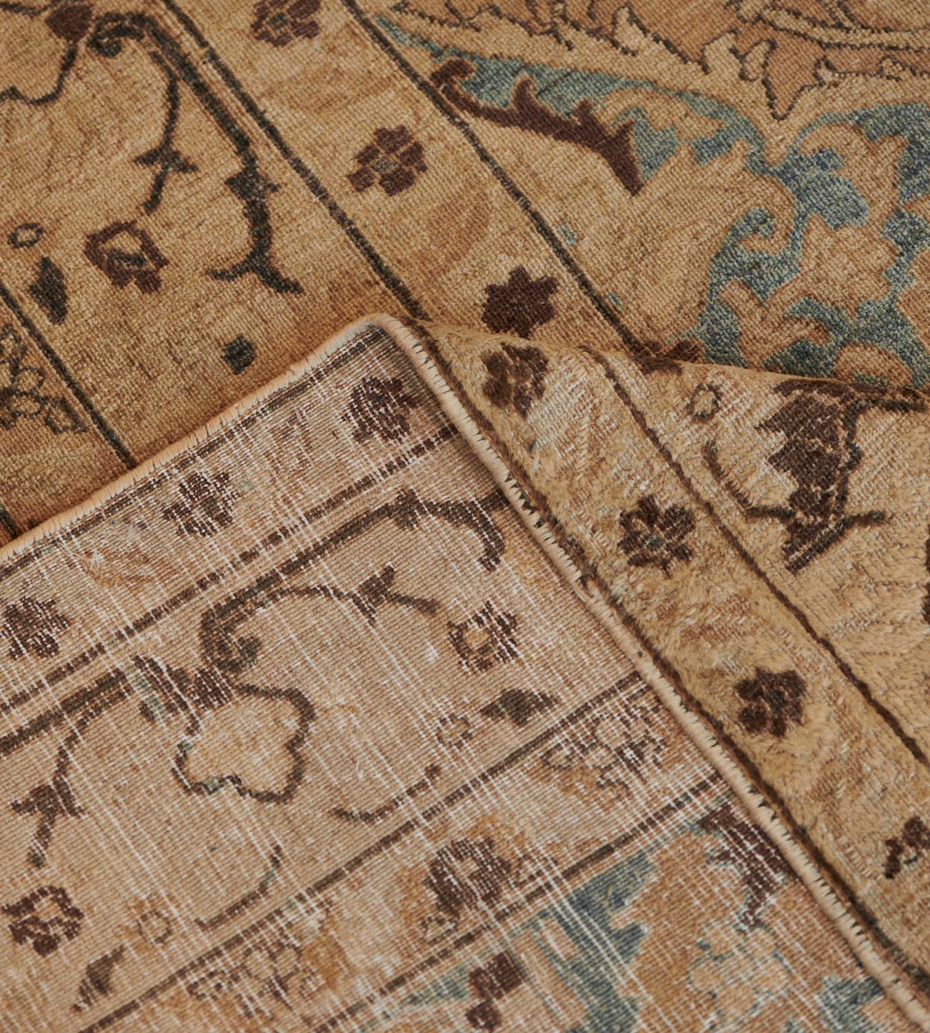 Dieser antike, um 1900 entstandene persische Teppich aus Chorasan hat ein biskuitbraunes Feld mit einer Blumenranke, die sich um zwei Säulen aus zwei hellsandgelben, gestuften Rauten mit Palmettenanhängern windet, die jeweils eine zentrale