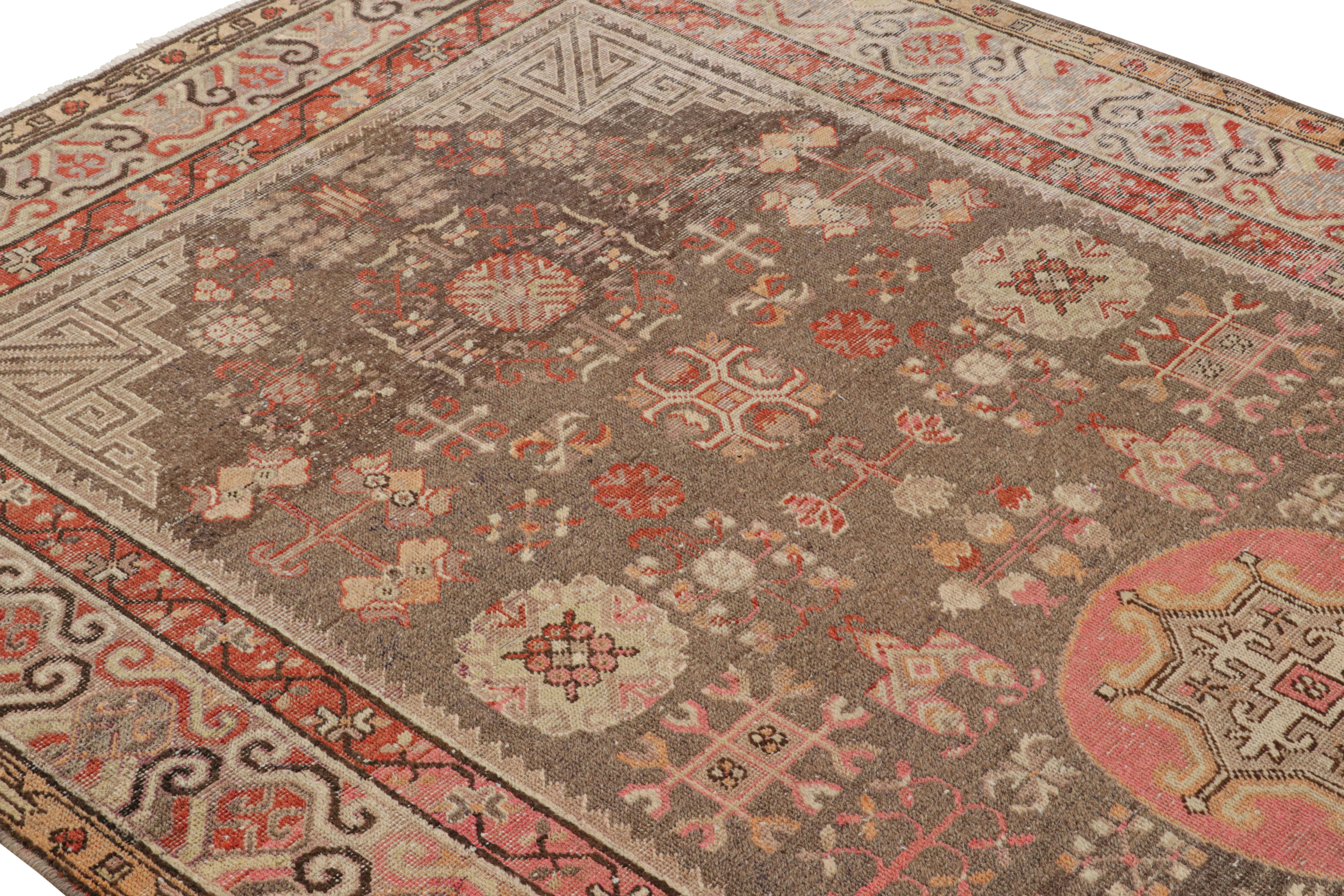 A 5 x 11 antique rug of Khotan design lineage, hand knotted in wool from East Turkestan, circa 1920-1920. Enjoying a medallion pattern in all over style with beige-brown and pink hues of lesser-known variety in this family. In good condition for its