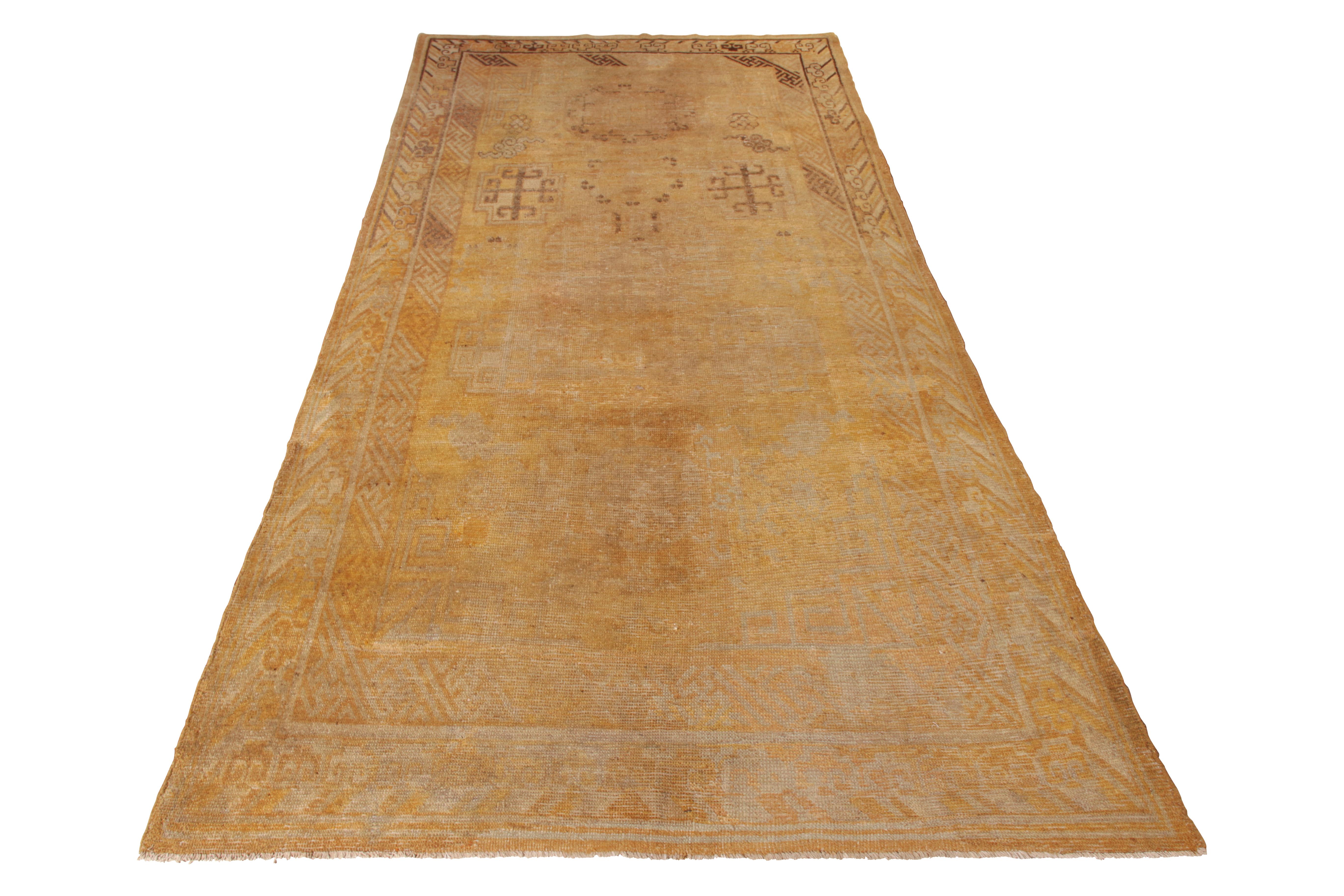 An antique 5 x 9 Khotan rug in beige-brown and gold, hand knotted in wool from East Turkestan, circa 1920-1930. Some distressed to the field, depicting ornate medallion patterns among the variety of intriguing oriental symbols this lineage