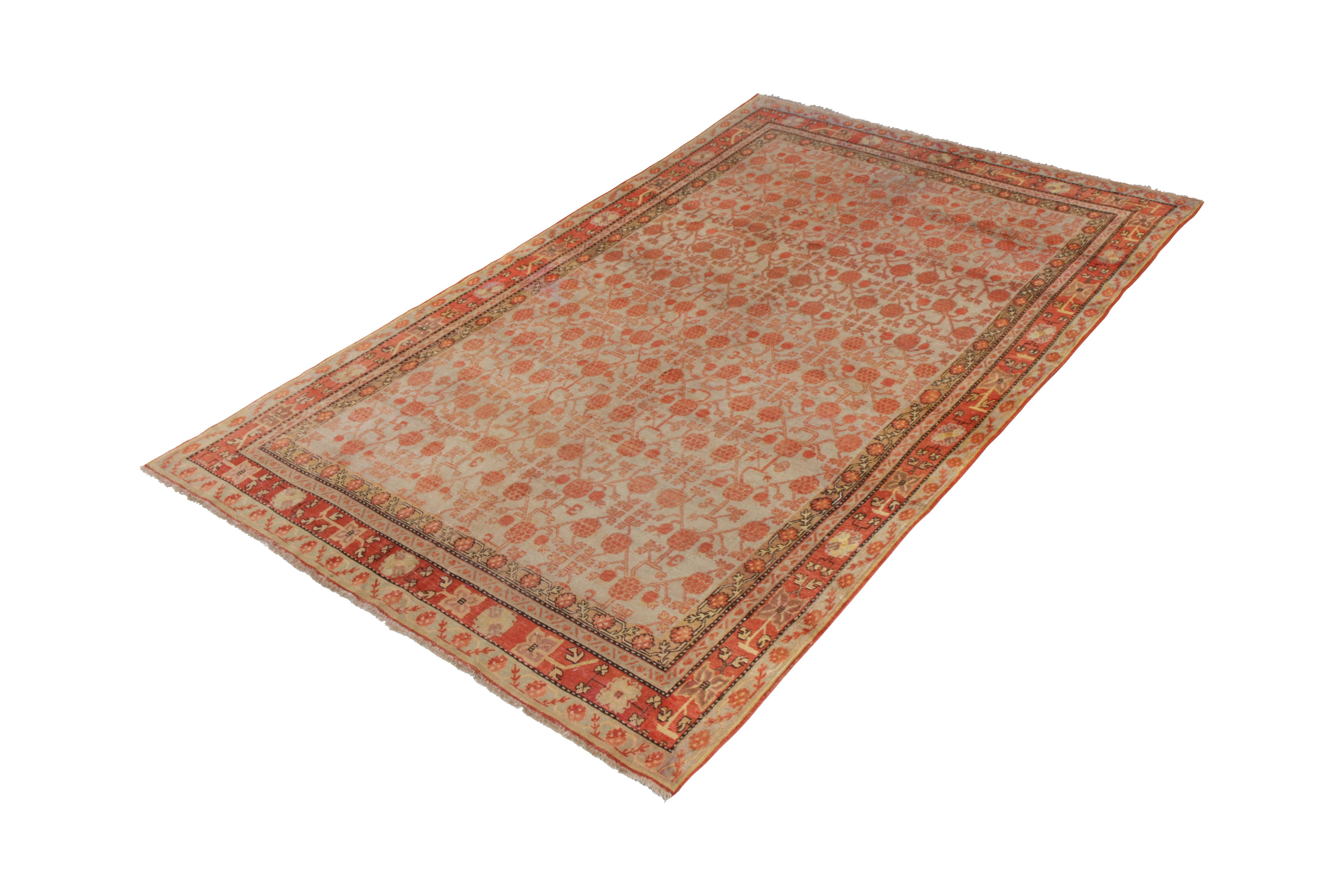 An 8 x 13 Khotan rug in red and blue, hand knotted in wool originating from East Turkestan, circa 1910-1920. This particular antique Khotan rug exemplifies ancestral pomegranate patterns in a smart sense of movement and cultured air. A rich variety