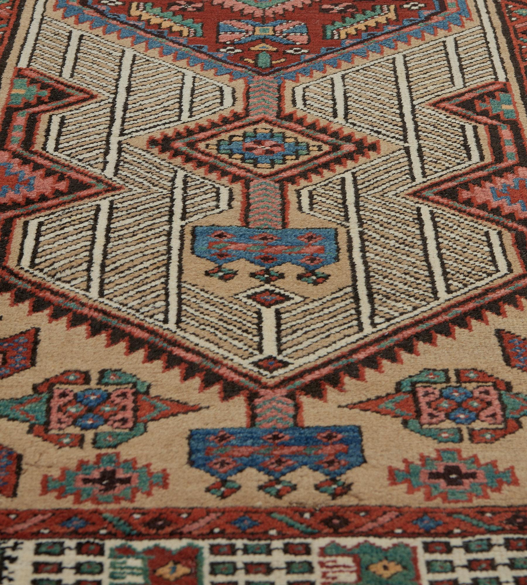 Dieser traditionelle, handgewebte persische Serab-Teppich hat ein beigefarbenes Feld mit gegenläufigen geometrischen Streifen, die zwei gezackte Rautenmedaillons in einer elfenbeinfarbenen geometrischen Bordüre einschließen.