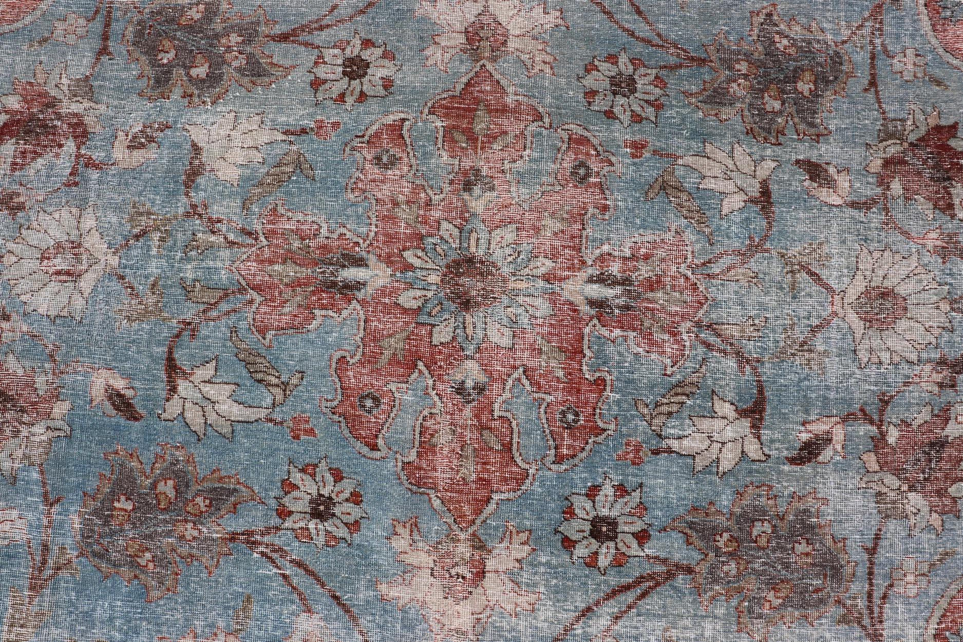 Cet antique tapis persan Tabriz Khoy présente un motif floral subgéométrique multicolore sur un fond rouge. Une bordure complémentaire à plusieurs niveaux englobe la totalité de la pièce, ce qui lui permet de s'adapter merveilleusement à une grande