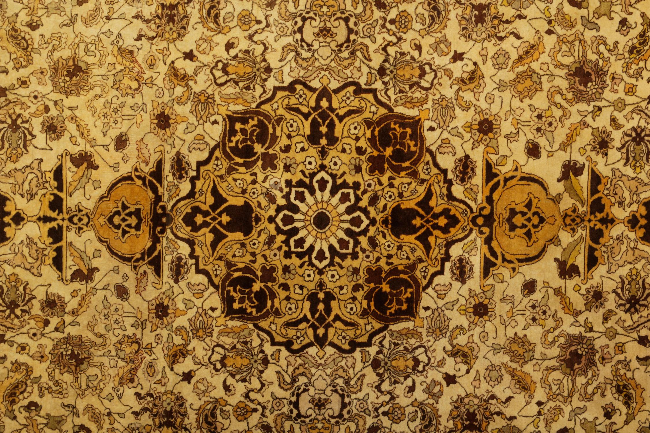 This Antique oriental rug was woven in the 1920s and features a gold, beige gold background that contrasts beautifully with the brown and black accents. The central and surrounding design is a symmetrical pattern revealing floral and botanical