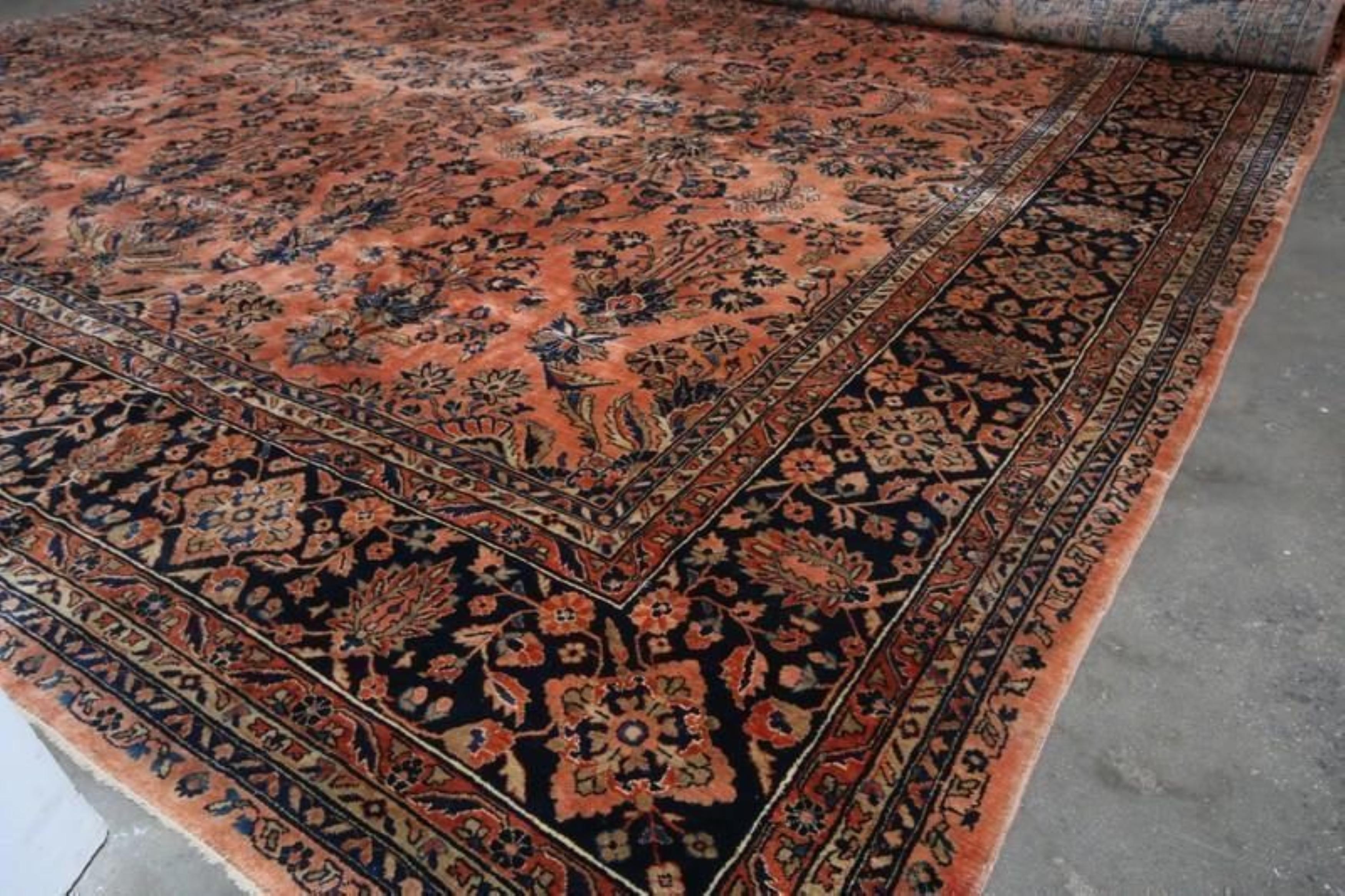  A 12x21 antique Persian rug of Sarouk lineage, hand knotted in wool circa 1920-1930. Enjoying one of the most exciting pallets of a traditional rug in a rich blue and orange, playing with black and red tones across a gracious all over floral