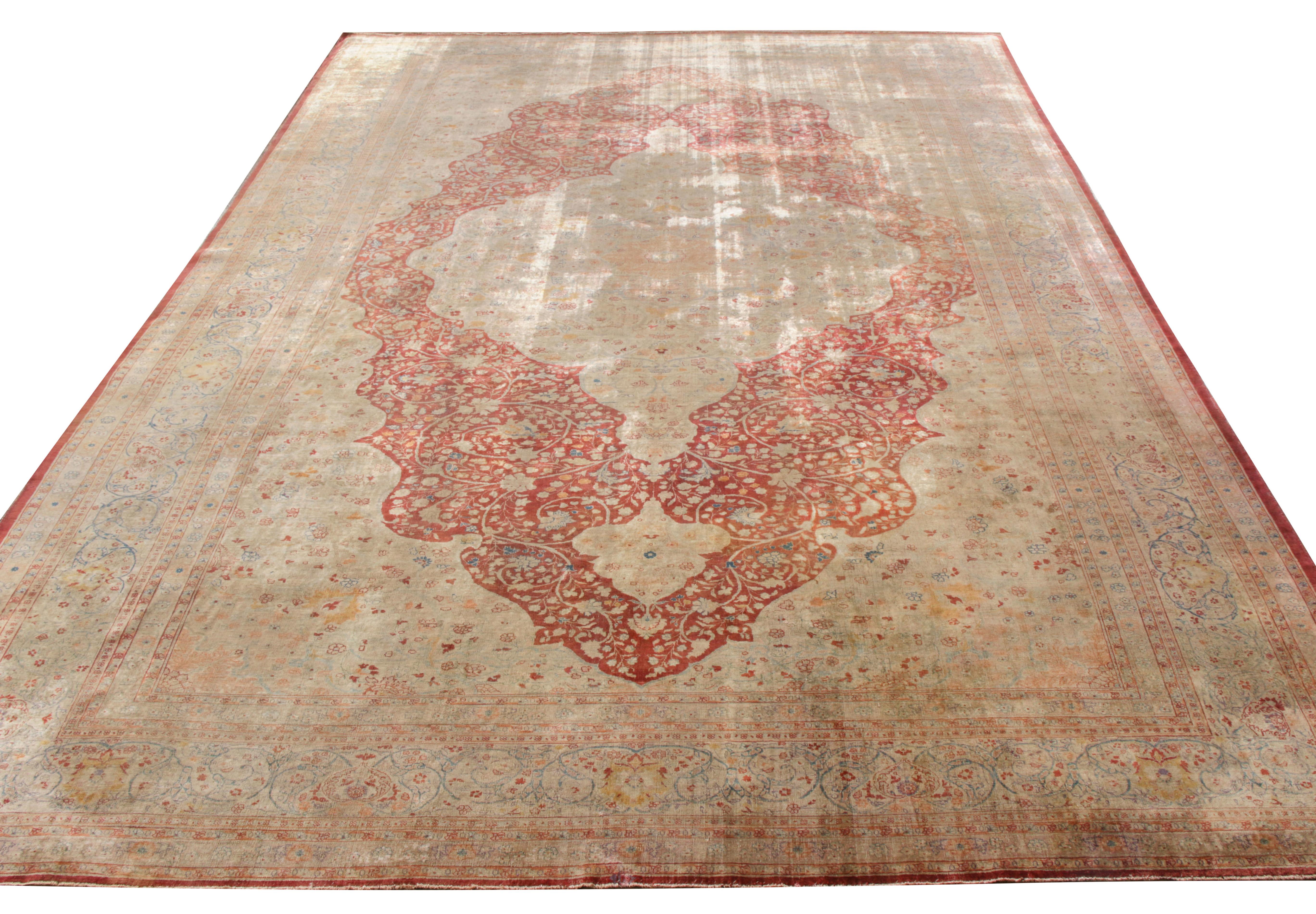 A hand-knotted antique Tabriz rug originating circa 1920-1930 relishing a sumptuous floral medallion in a luscious red and beige-brown hues The striking tones of rich red are set off with accenting hues of blue, white and orange in the vivid