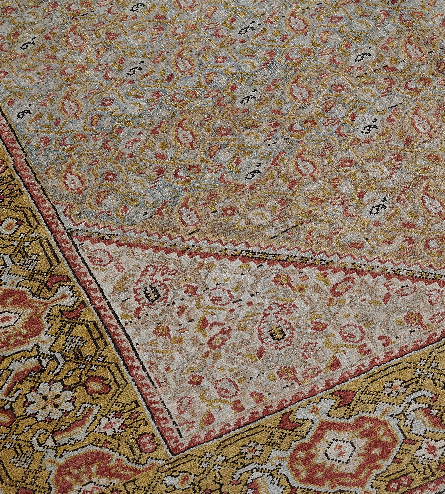 This antique Malayar rug has a shaded mole-grey and light blue field with an overall pistachio-yellow and brick-red herati-pattern, the part lozenge spandrels similar, in a pistachio-yellow border of ivory and brick-red turtle-palmettes linked by an