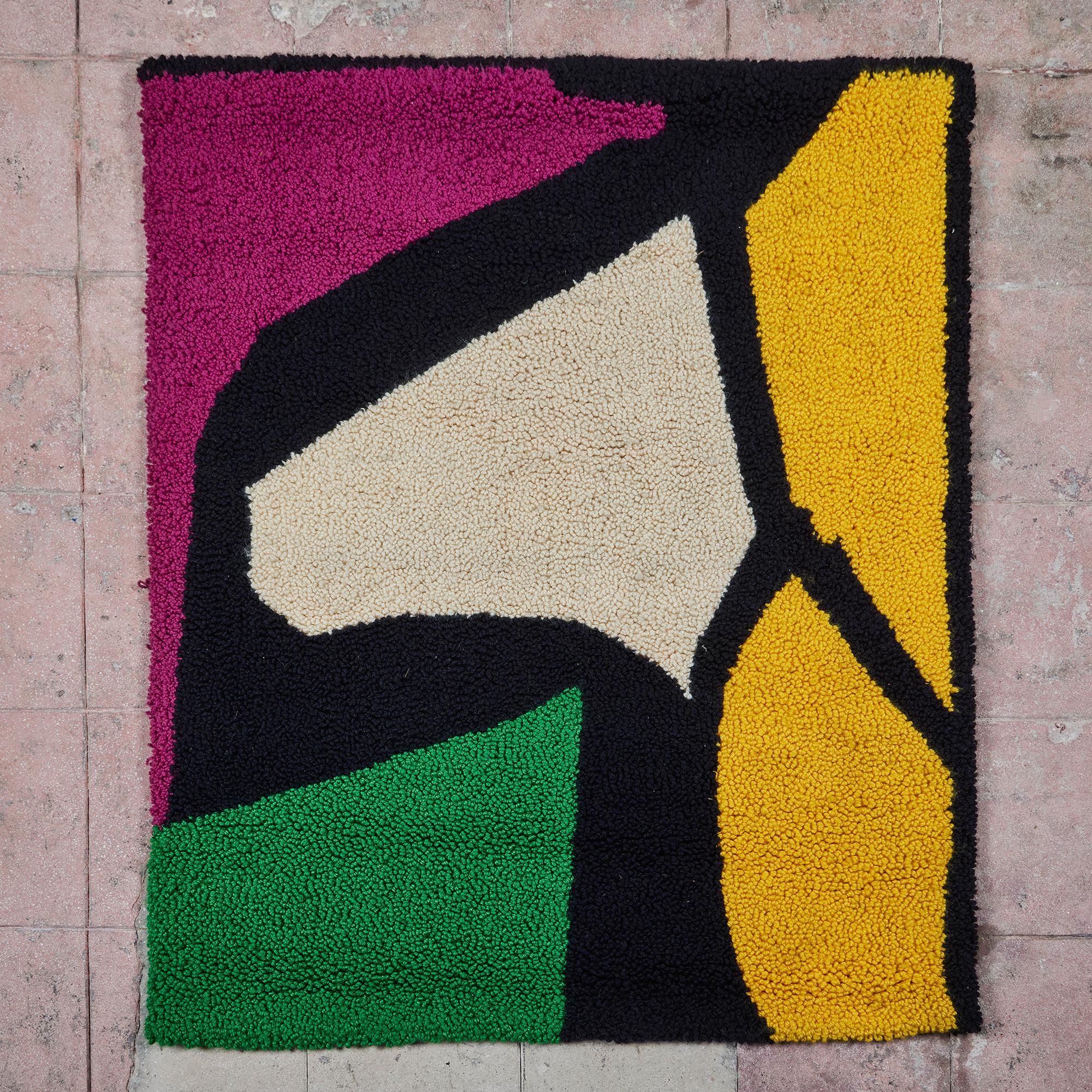 Handgeknüpfter Farbblockteppich, ca. 1972, USA. Ein farbenfroher Wandbehang mit schwarz umrandeten Formen. Die Formen variieren in den Farben Gelb, Lila, Grün und Creme. Das Stück wird an einer festen Stange auf der Rückseite aufgehängt. Signiert