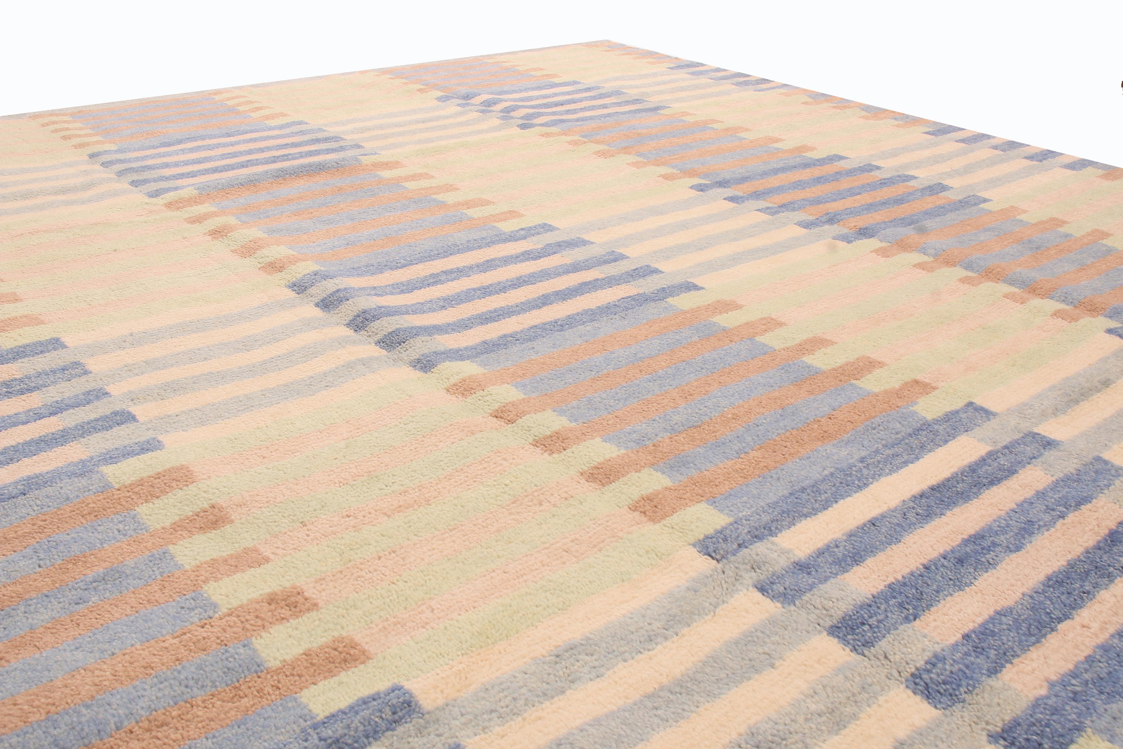 Originating from India, this geometric hand knotted wool rug employs a borderless, contemporary all over field design strongly resembling antique and vintage Bauhaus patterns. The finely woven ocean blue, cream pink, brown, and green colourways