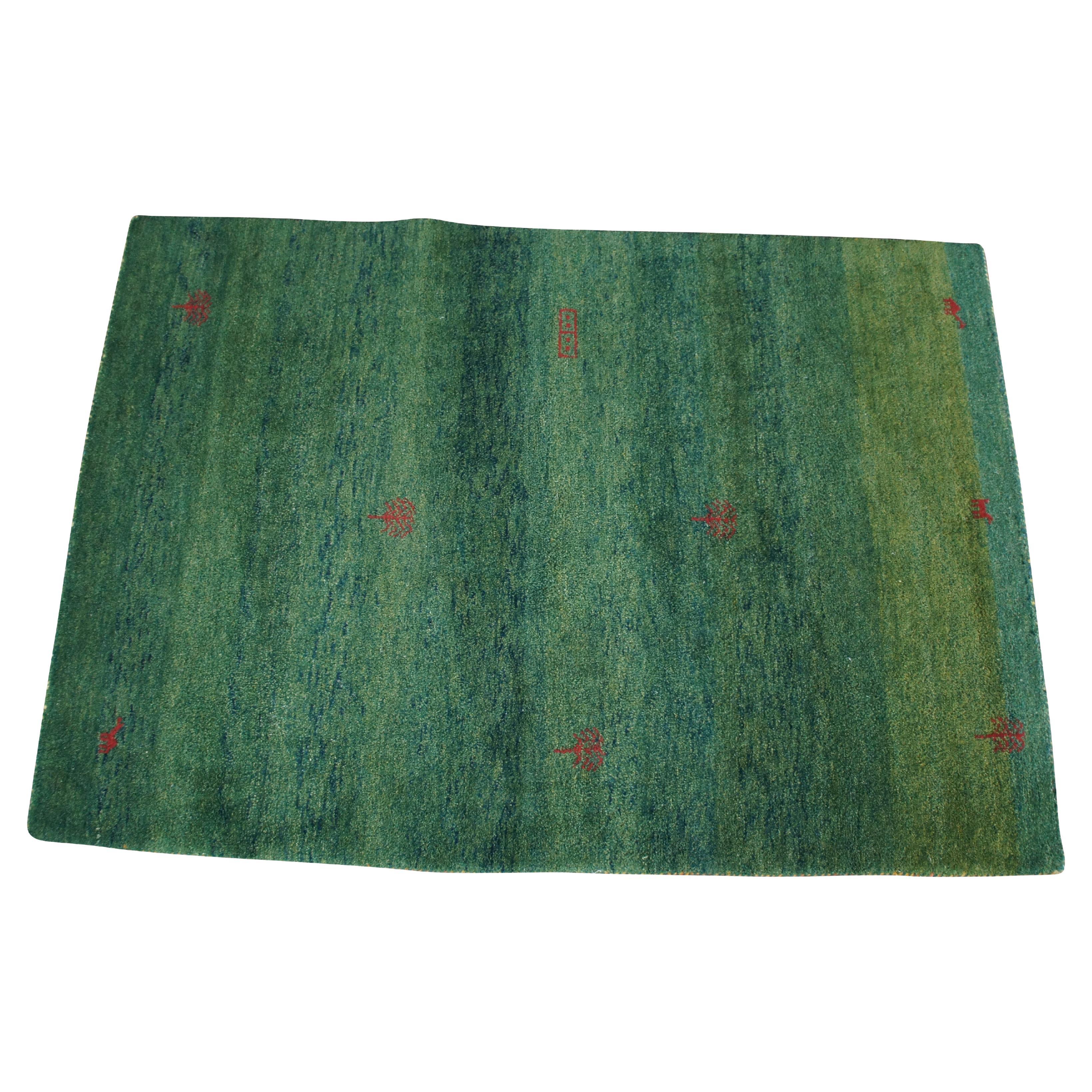 Tapis indien noué à la main en laine Gabbeh.  Elle présente un design Modern avec des piles vertes rehaussées d'arbres et de personnages rouges.

Dimensions :
75