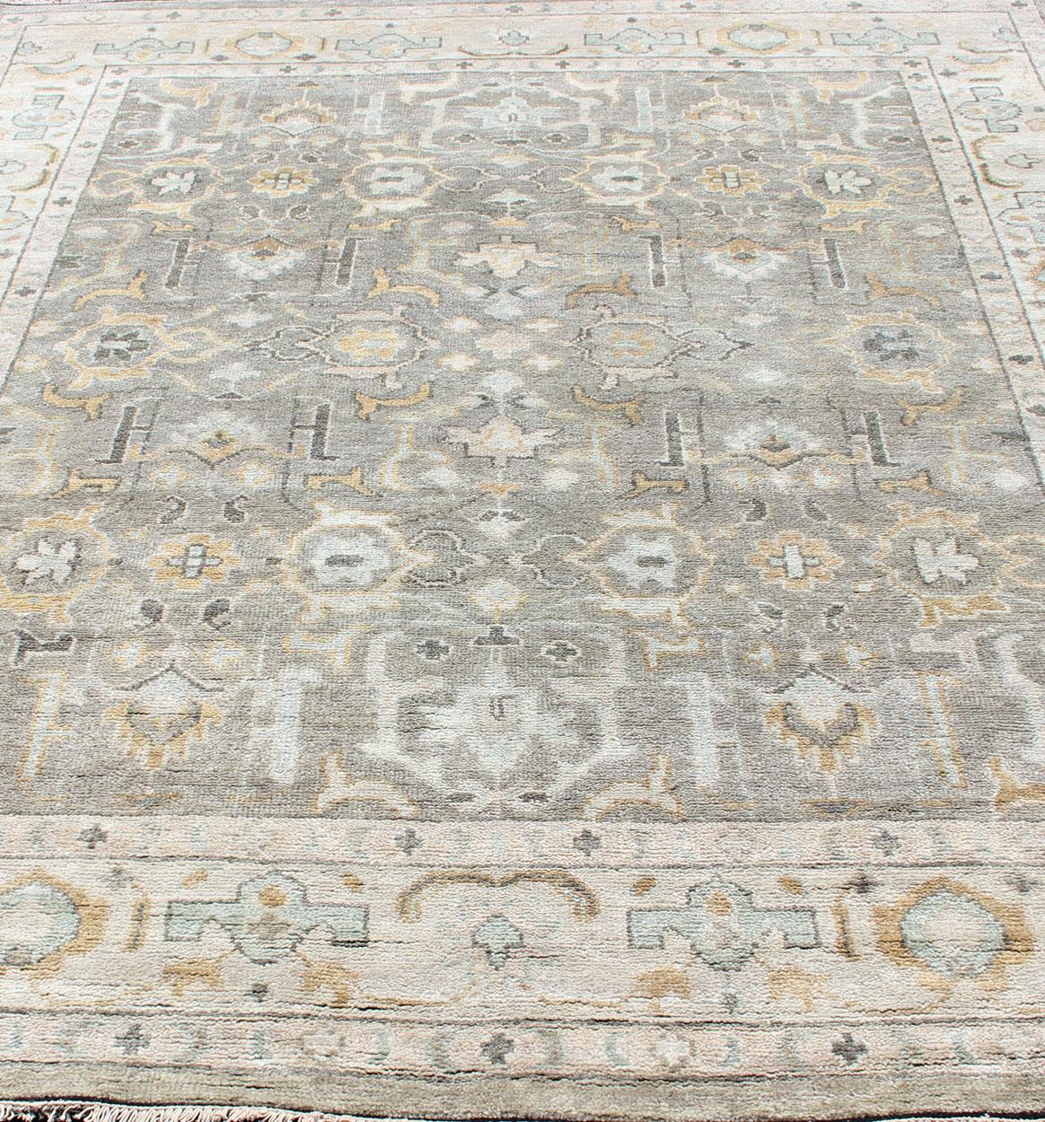 Hand-Knotted Indian Oushak in Faded Green, Taupe, Gold and Cream. 
Measures 8'0 x 10'2
This Indian Oushak was hand-knotted with wool during the 2010's. The cream border has gold and light blue repeating medallions. The faded taupe field displays a