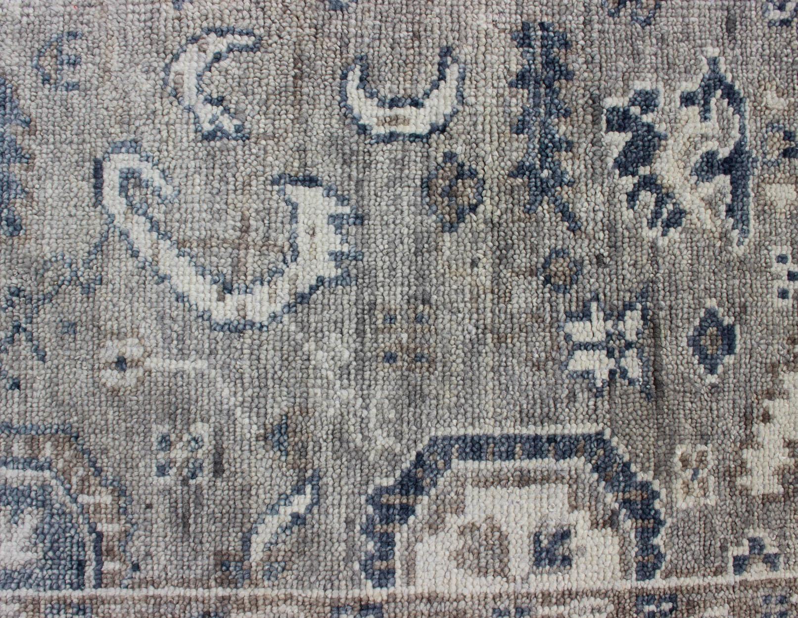 Hand-Knotted Indian Wool Oushak Rug in Cool Neutral Tones. 
 Measures 8'0 x 9'9 
This woven art was hand-knotted in India, where many rug makers take the Turkish Oushak style and recreate it with their own cultural influences. This mature piece