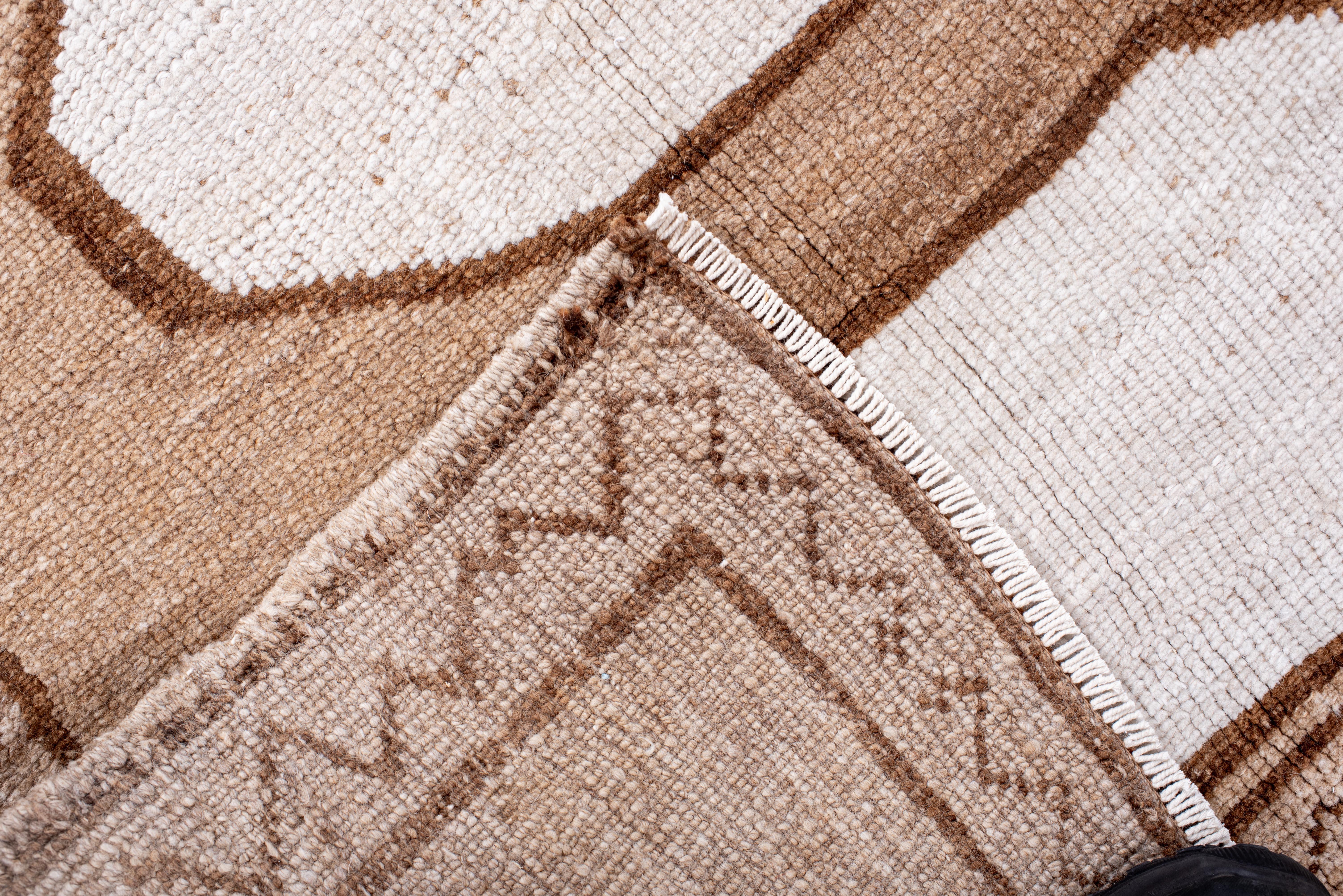 Questo tappeto vintage di Kars, proveniente dall'Anatolia orientale, presenta un'estetica straordinariamente moderna grazie alla sua disposizione minimalista di medaglioni ottagonali ripetuti. Il campo è un gradiente di caldo cammello e morbido