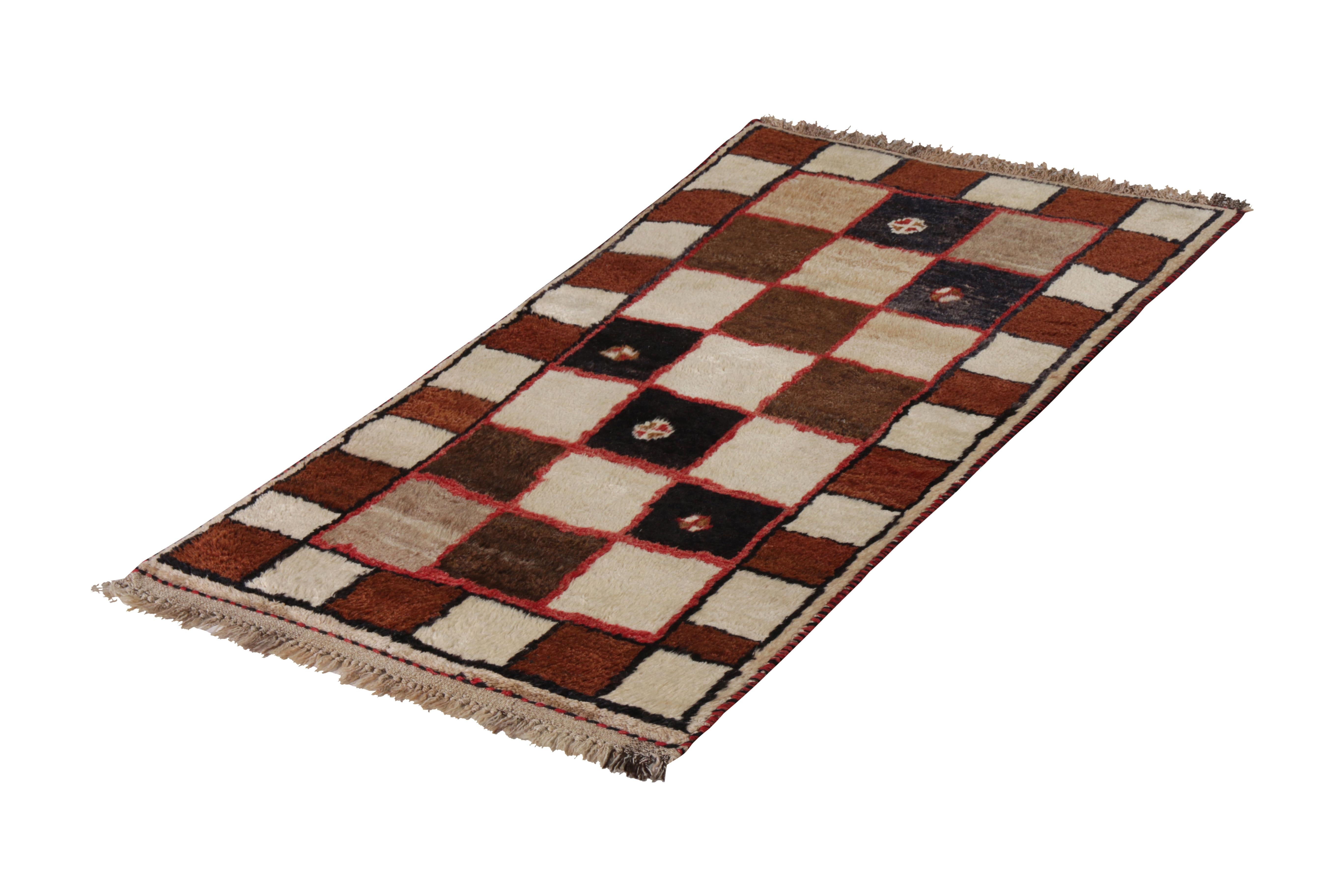 Hand knotted in wool originating circa 1950-1960, this vintage Persian rug connotes a midcentury Gabbeh rug design in excellent condition, enjoying a versatile 3 x 5 size and a comfortable beige-brown colorway in complementary geometry. A tasteful