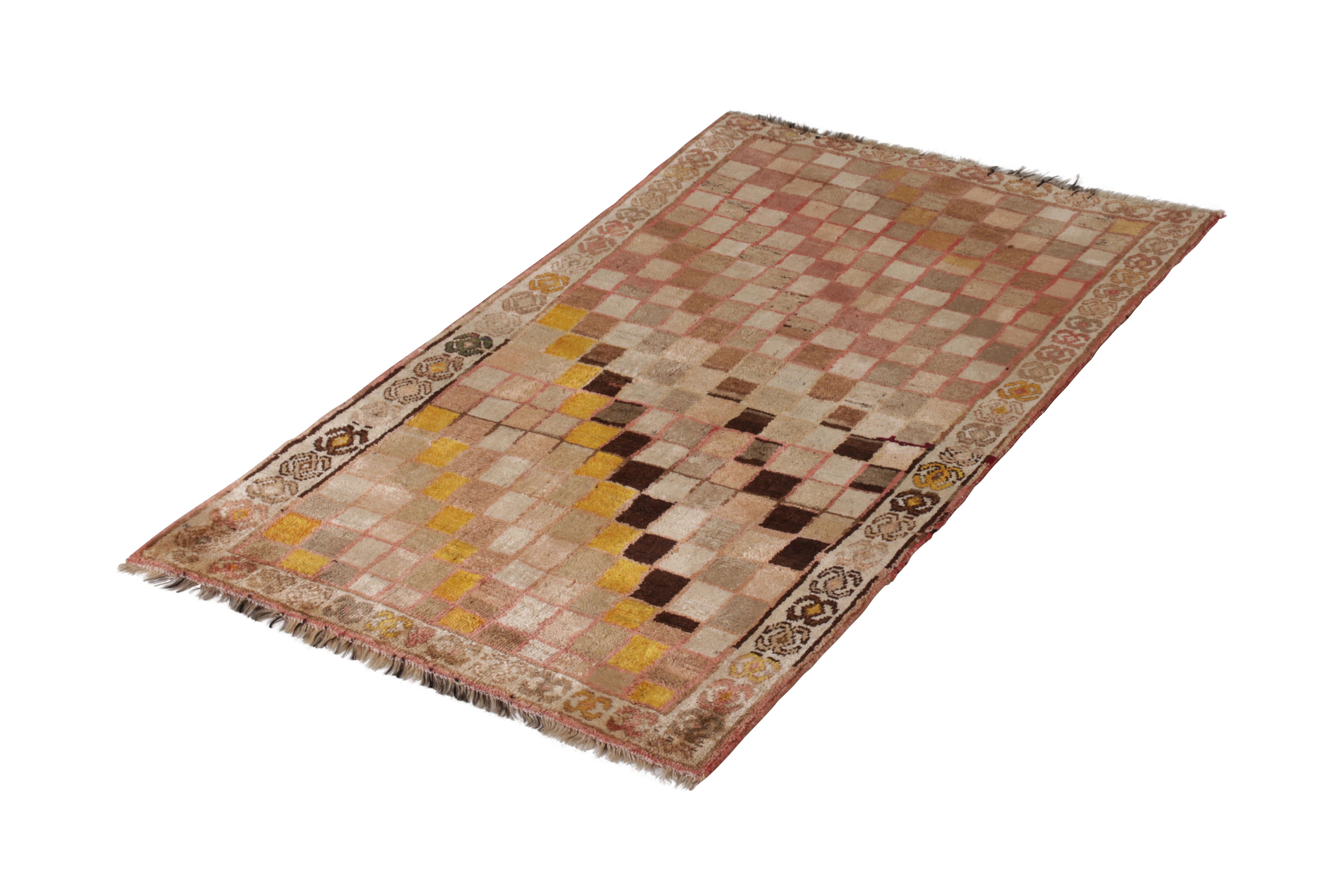 Hand knotted in wool originating circa 1950-1960, this vintage Persian rug connotes a midcentury Gabbeh rug design in a fabulously unique modern colorway, employing a classic beige-brown with a prevailing pink hue among several intriguing, colorful