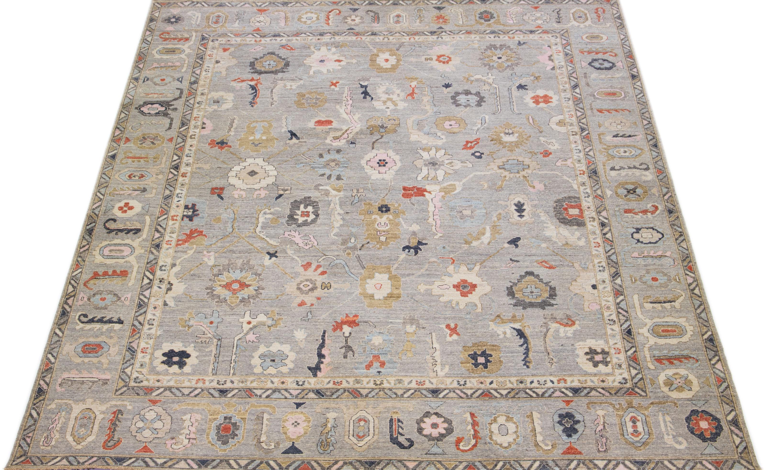 An exquisite oversized Sultanabad hand-knotted wool rug is presented, showcasing a stunning gray field with a design frame. The rug further highlights rust, blue, and pink accents in a breathtaking floral motif that embellishes the entire rug