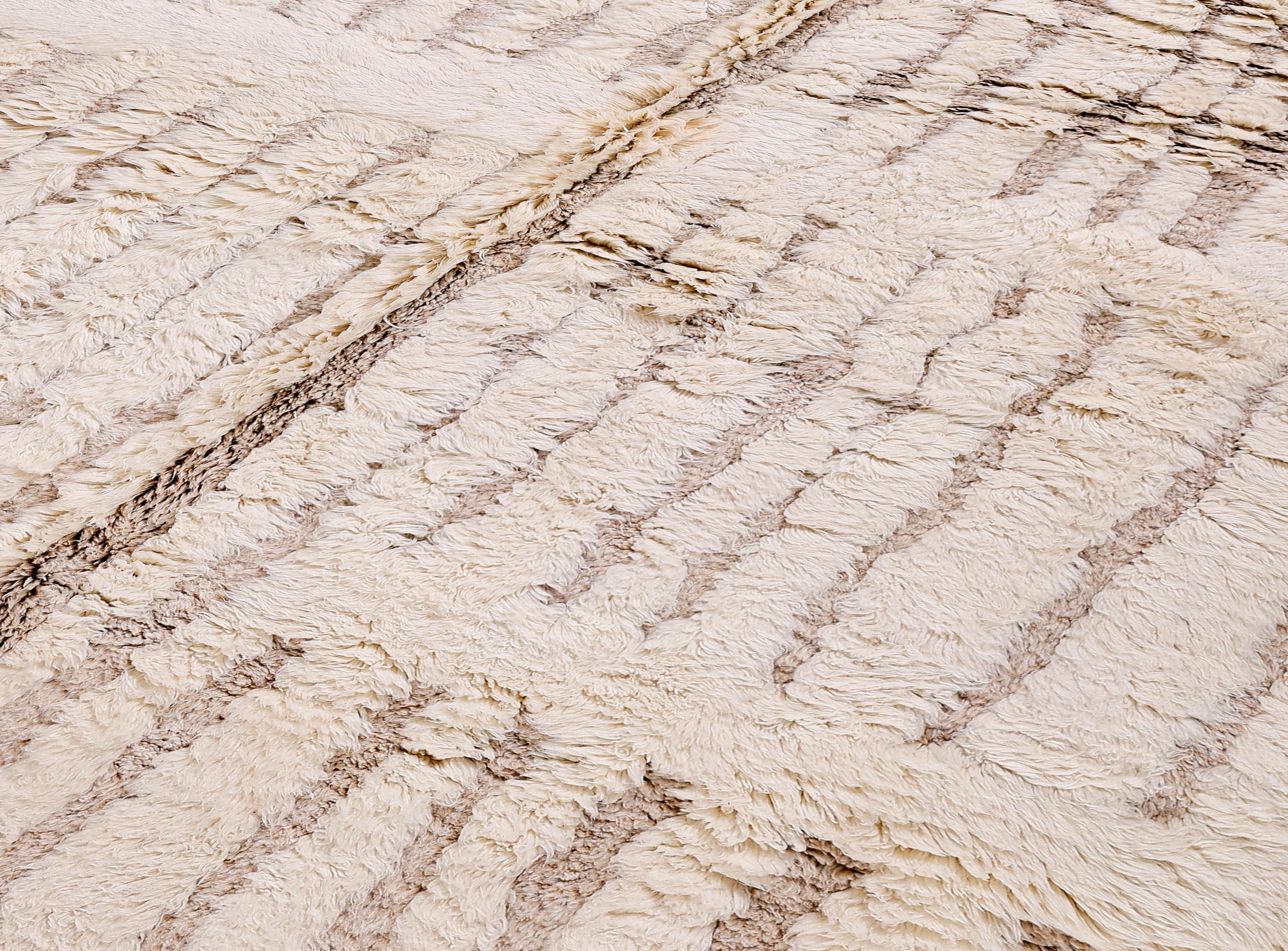 Questo splendido tappeto marocchino Beni Ourain, annodato a mano, è un'interpretazione moderna del minimalismo tribale, realizzato in lana naturale in una tavolozza di morbidi colori crema e tortora. Con il suo pelo alto e la sua consistenza, questo