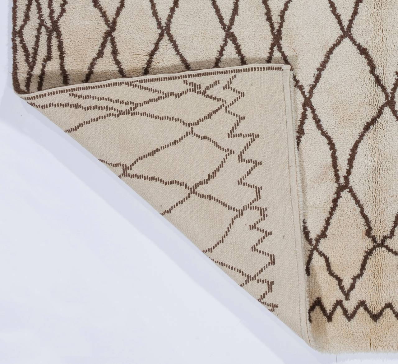 Una moderna alfombra marroquí hecha a mano con lana de oveja natural sin teñir de color marfil/crema y marrón, con un toque de rojo teñido natural en el extremo inferior. 

🧵 Detalles del producto:
🧶 Material: 100% Lana natural
Técnica: Anudado a