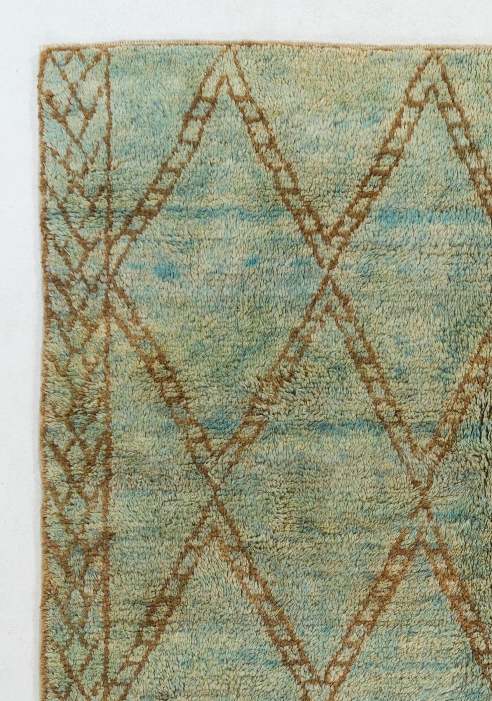 A Moroccan Berber design contemporary hand-knotted area rug made of organic wool in a sophisticated, warm and earthy color palette of olive green, brown and light blue. It features an all-over design of lozenge-shaped, wide-edged lattices and two