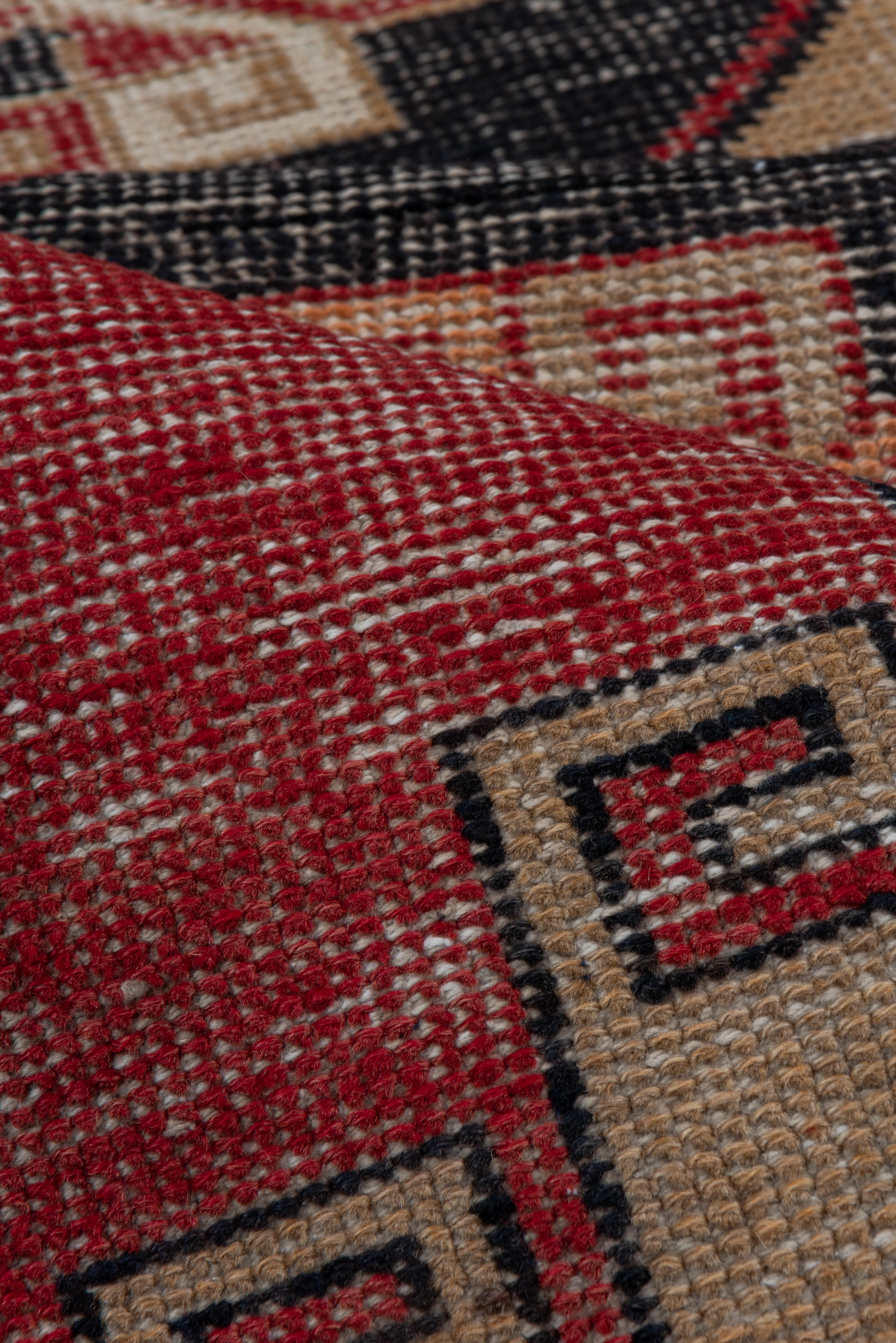 Dieser Vintage-Läufer aus Oushak zeichnet sich durch eine beeindruckende geometrische Komposition aus gestuften Medaillons in tiefem Anthrazit, Sandsteinbeige und verbranntem Rot aus, die durch stilisierte griechische Schlüsselmotive verankert sind.