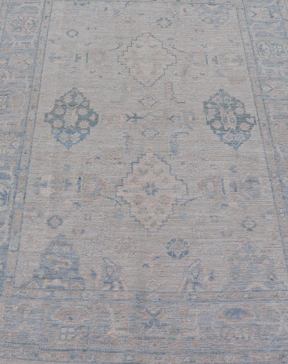 Hand-Knotted Oushak with a light blue background and tribal motifs. Keivan Woven Arts; rug AWR-10729 Country of Origin: Afghanistan Type: Oushak Design: Floral, All-Over Abstract-Tribal 
Measures: 4'0 x 5'4 
This Oushak presents centered motif
