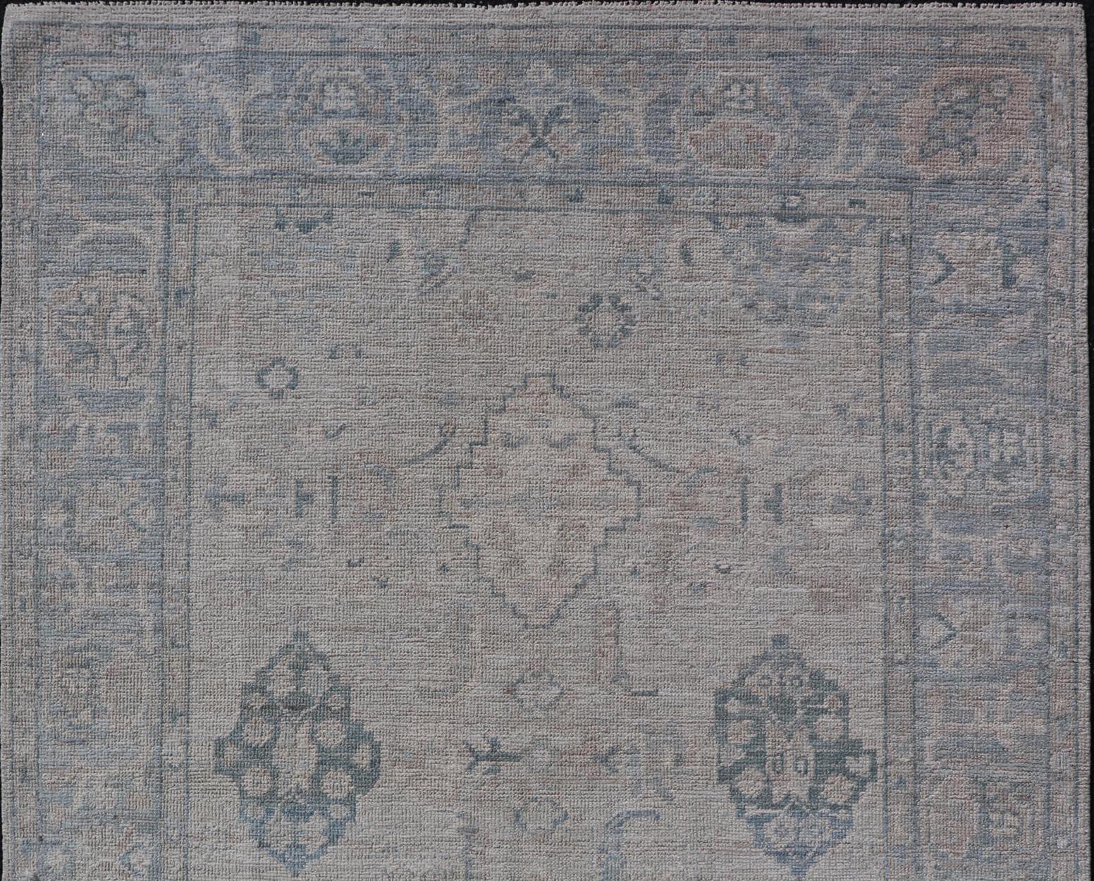 Wool Hand-Knotted Oushak with a Light Blue Background and Tribal Motifs For Sale