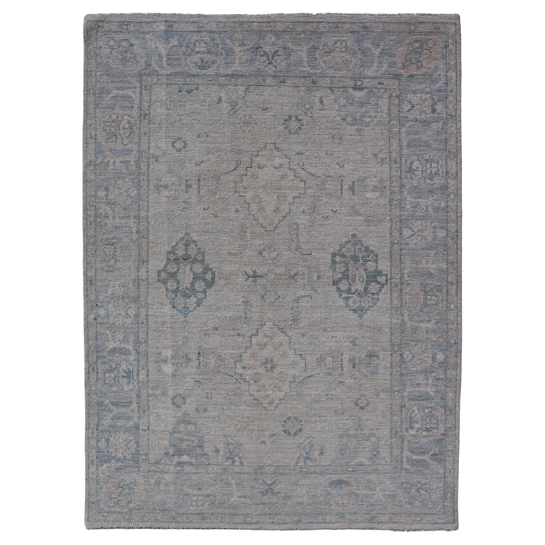 Hand-Knotted Oushak with a Light Blue Background and Tribal Motifs For Sale
