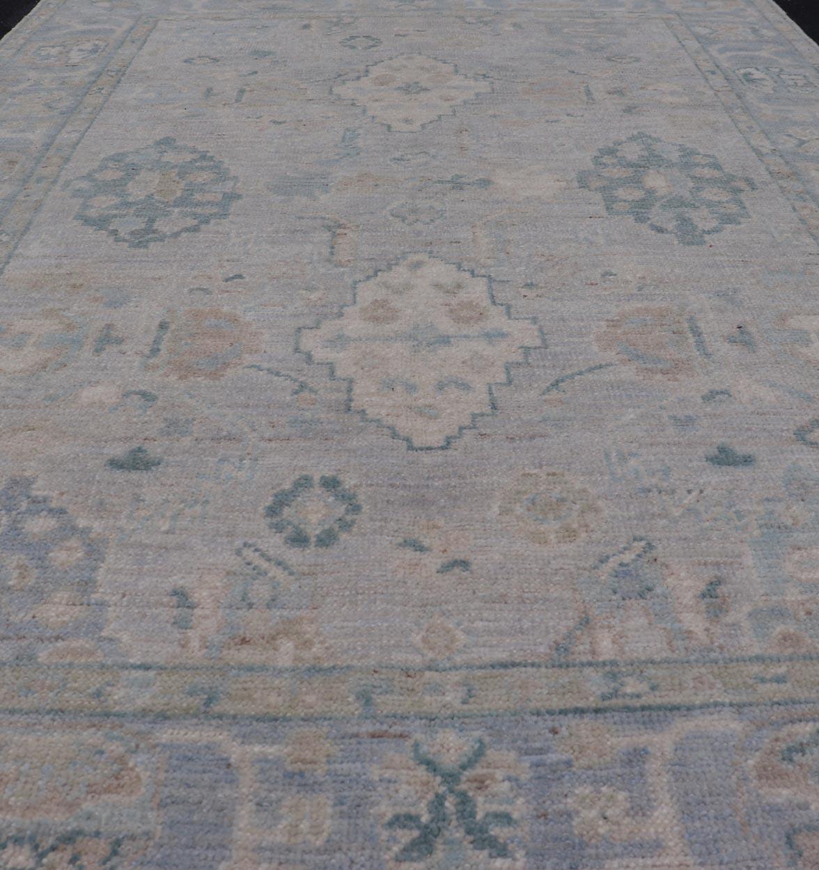 Hand-Knotted Oushak with a Light Blue-Gray Background and Tribal Motifs. Keivan Woven Arts; rug AWR-16951 Country of Origin: Afghanistan Type: Oushak Design: Floral, All-Over Abstract-Tribal. 
Measures: 3'10 x 6'0 
This Oushak presents centered