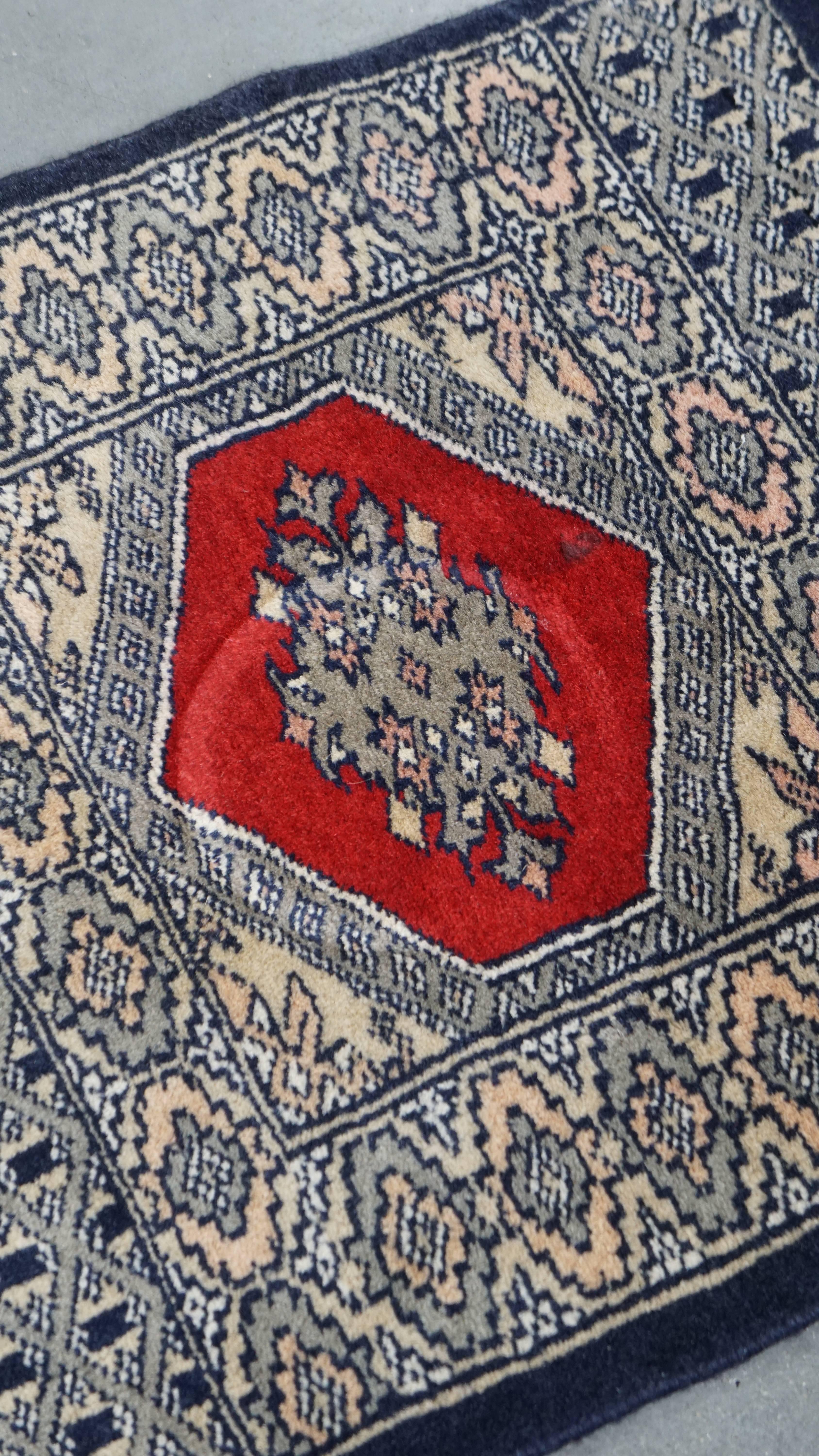 Offered here is this hand-knotted decorative rug or tablecloth, featuring a fine pattern in dark blue and red tones, measuring 47x46 cm. Bring a touch of charm and elegance into your home with this beautifully detailed piece. Its vibrant colors and