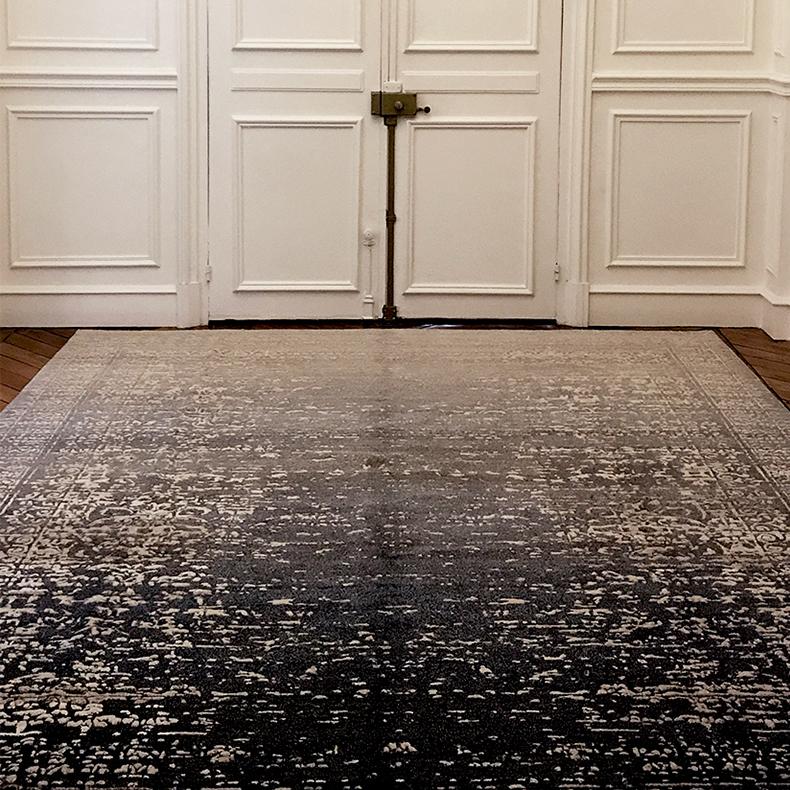 Ferrara Stomped Reverse is the name given by the designer, renowned maker of contemporary rug art Jan Kath. The tones of the low level wool of this rug grade from a deep blue gray to a light gray. The intricate up level silk fibers are an ivory