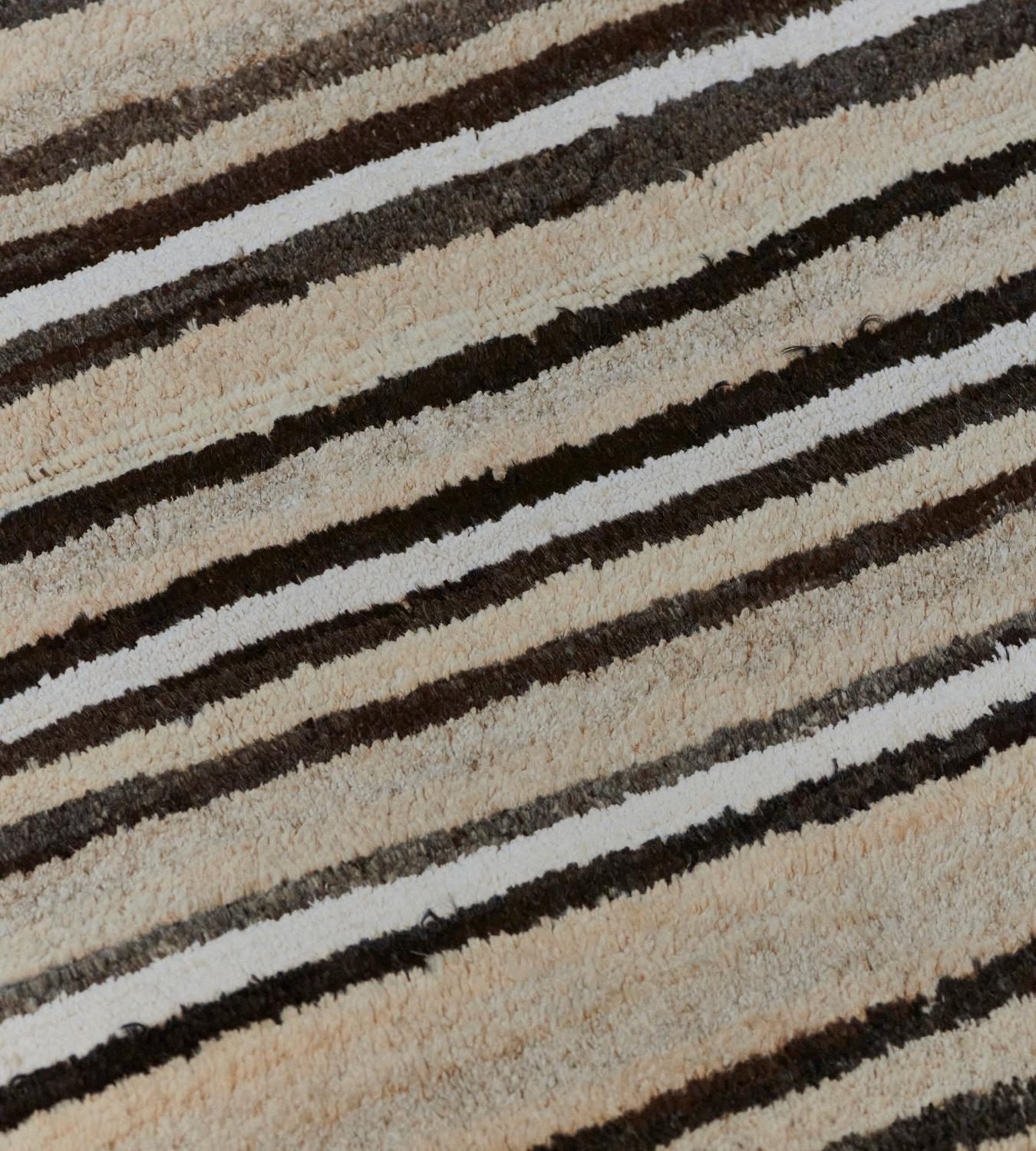 This hand-woven, deep pile Turkish Deco rug has stripes of varying widths of beige, ivory, charcoal, and black.