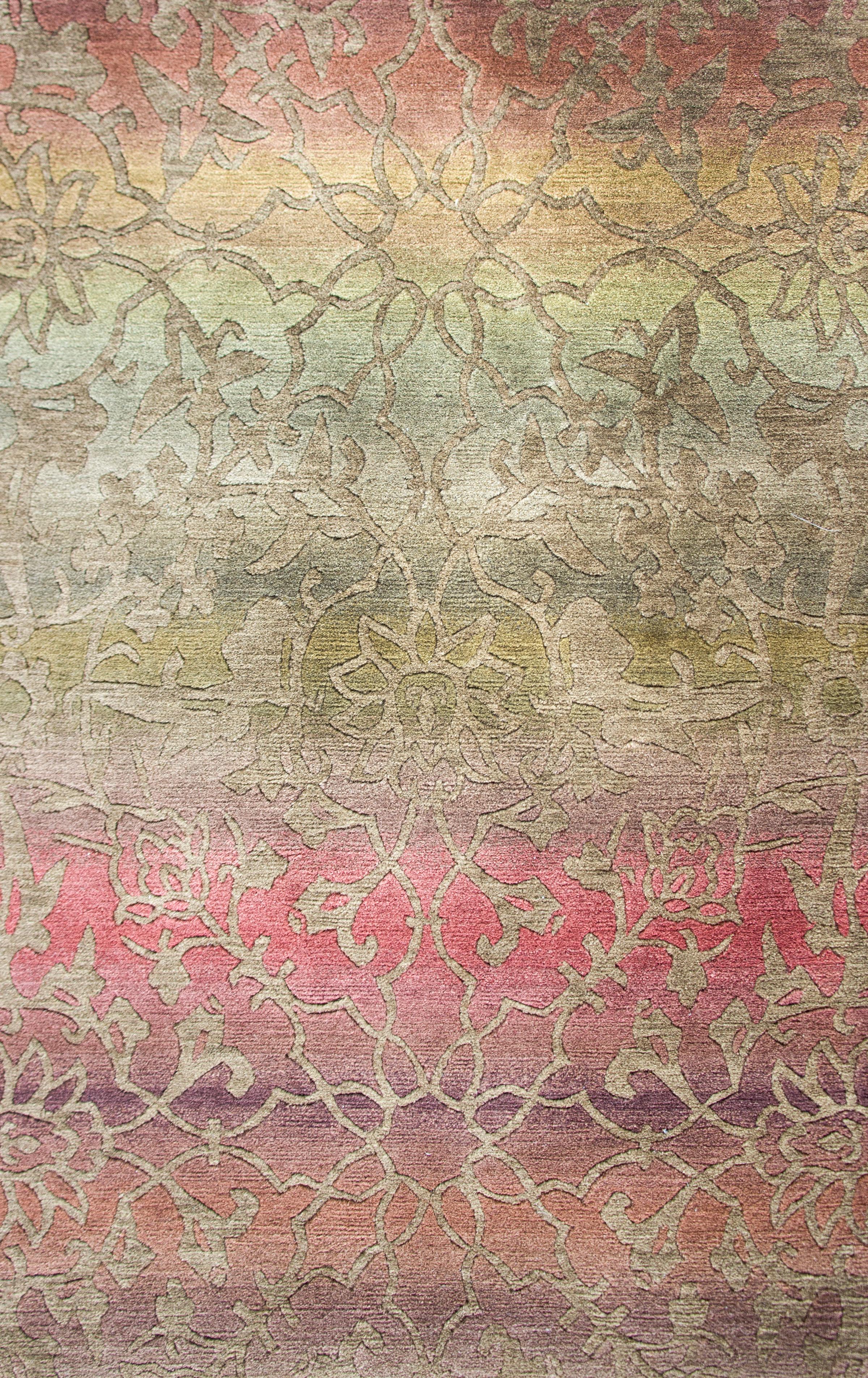 A sweet contemporary hand-knotted Tibetan rug with an ombré rainbow background overlaid with a central lotus flower surrounded by a lacy scrolling vine pattern woven in a neutral beige color.