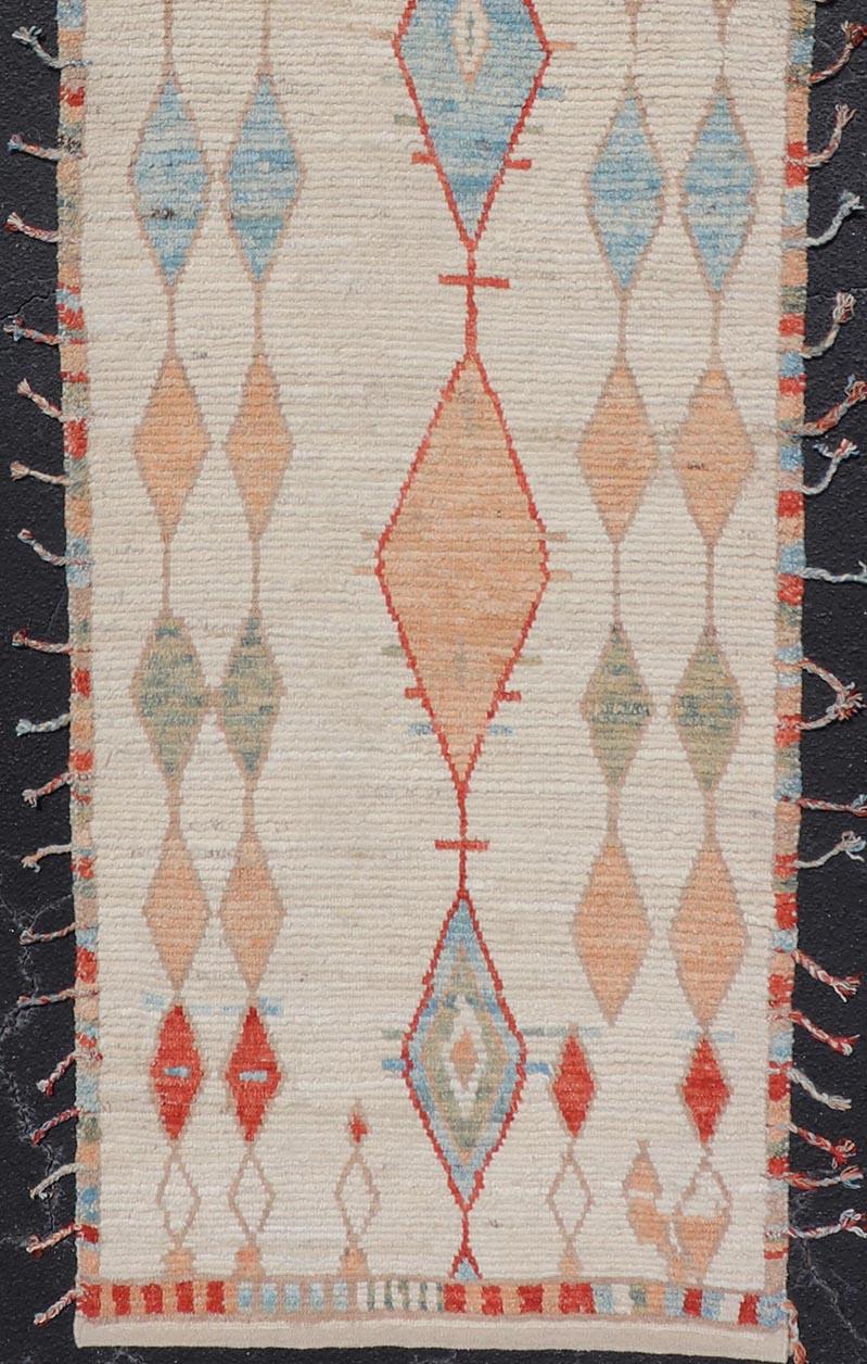 This modern casual tribal runner has been hand-knotted in wool. The rug features a modern Sub-geometric diamond design, rendered in multicolor and enclosed within a complementary border; this rug is a superb fit for a variety of Classic, modern,