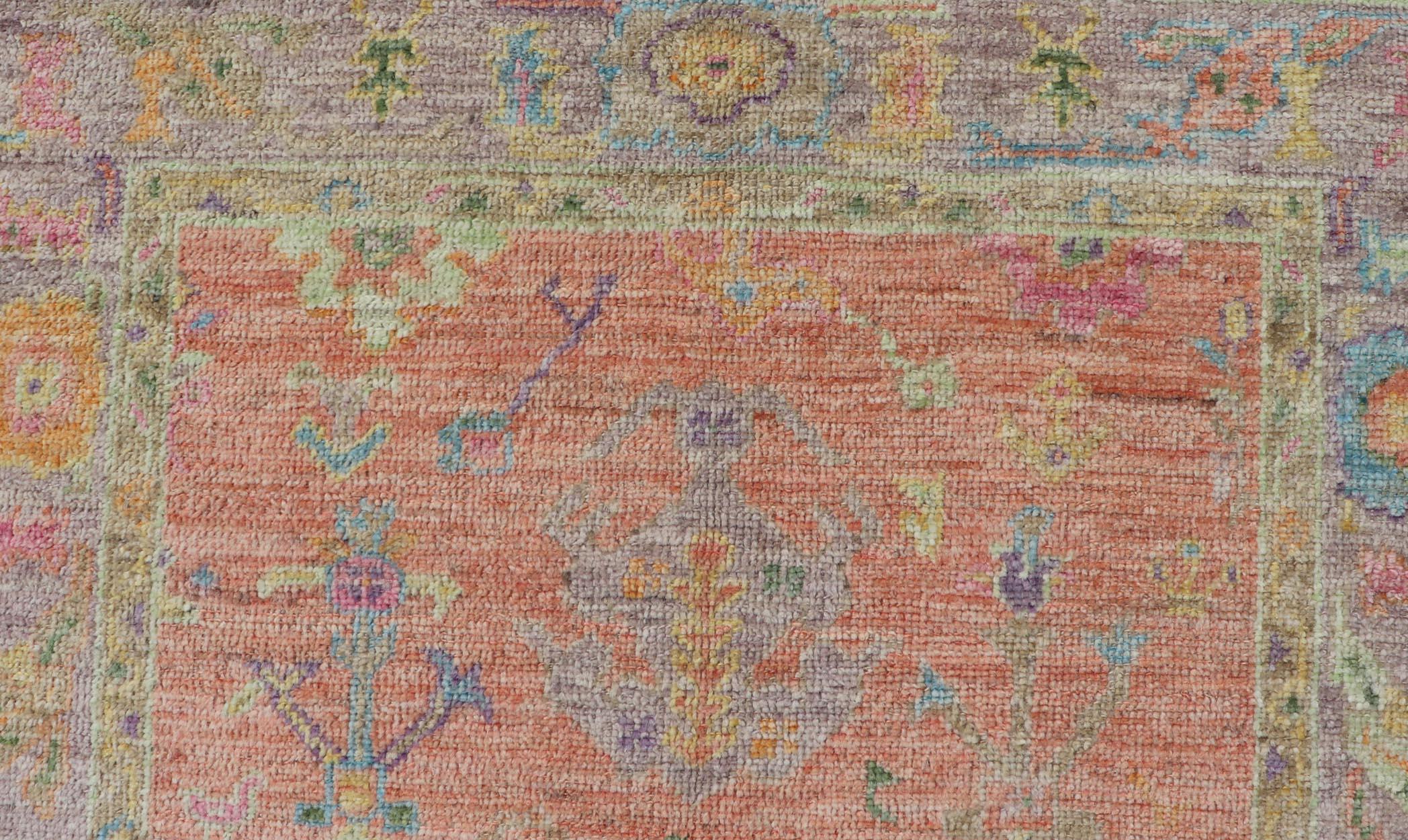 This very unique piece has a wide array of bright colors, starting with a faded orange background and a light lilac border, showcasing fuchsia, electric blue, violet, orange and seafoam green. The field design showcases the same colors in a tribal