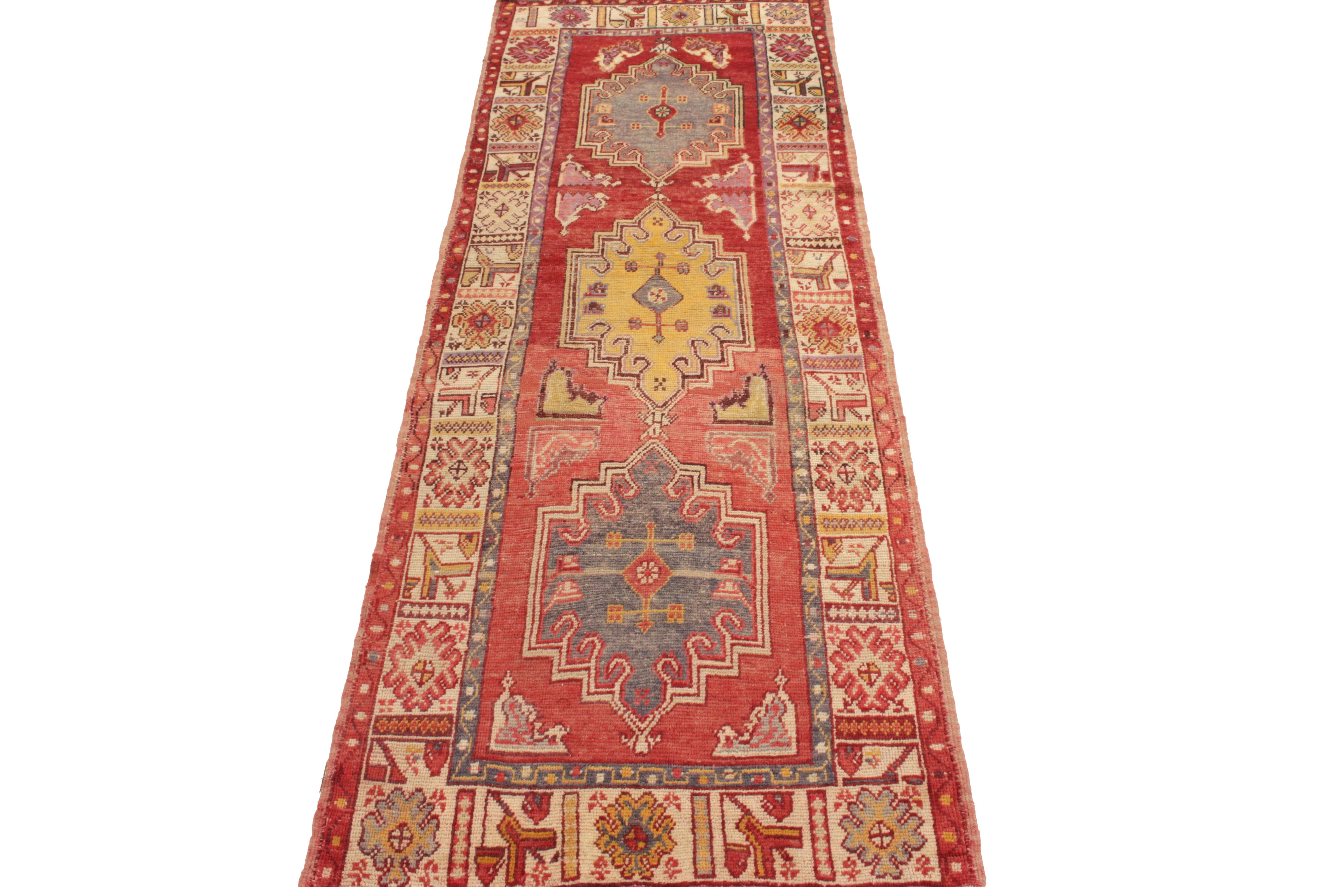 Originating from Turkey circa 1950-1960, a vintage 3 x 9 mid-century pile runner connoting Anatolian design lineage. Hand-knotted in wool, deliciou pink-red and bright white frame hues of blue and gold in a regal medallion pattern, complemented by