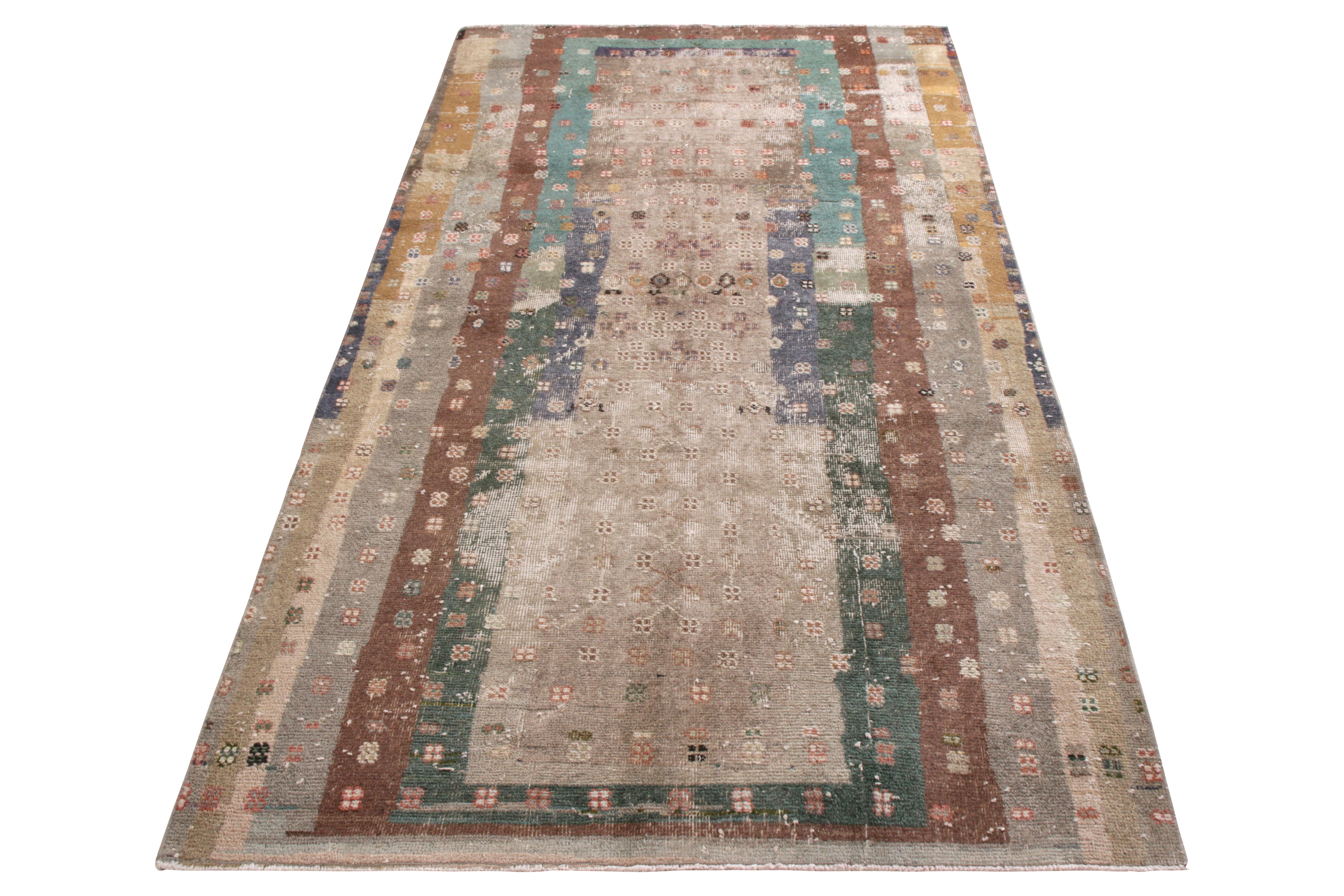 A 4 x 8 vintage rug in distressed boho-chic quality, hand knotted in wool originating from Turkey circa 1950-1960. Enjoying multicolor geometry against beige-brown hues in a portrait invoking playful abstraction and distinction underfoot.