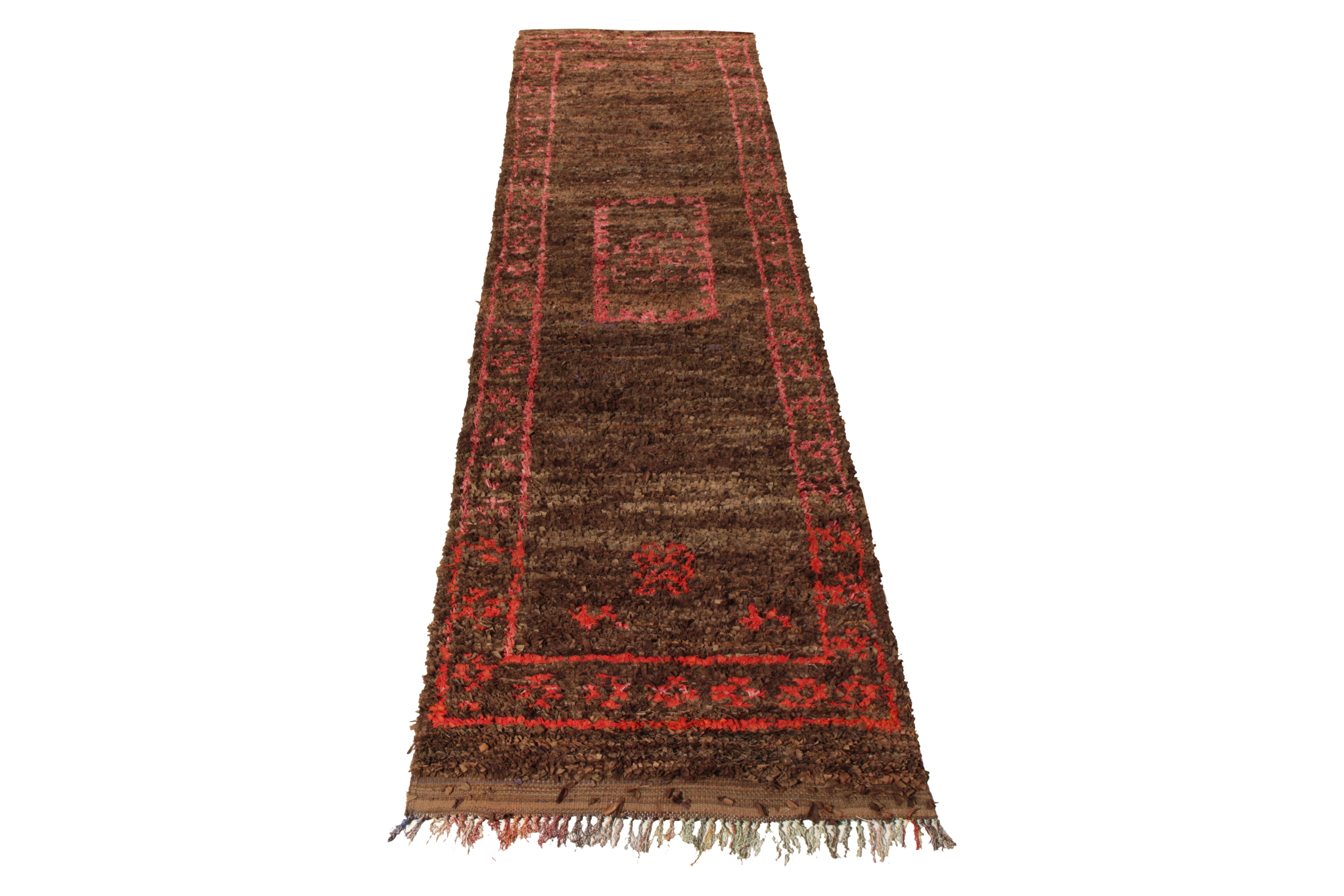 Hand knotted in Boucherouite fabric from Morocco circa 1950-1960, a vintage 4x13 Berber style Moroccan runner enjoying a unique colorway and medallion pattern. With tribal touches prevailing in the geometry, this pallet enjoys a warm red and pink