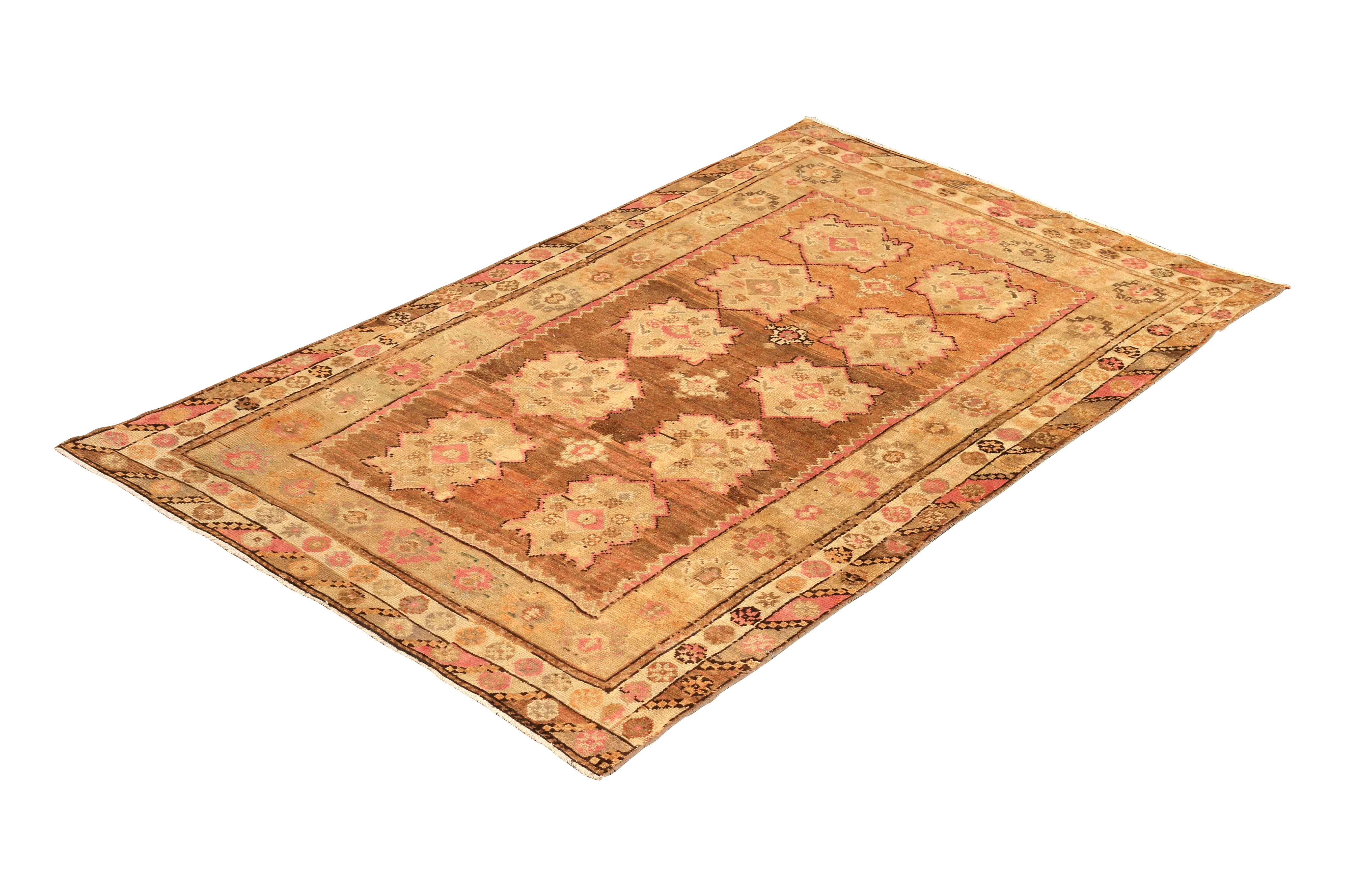 Hand knotted in wool from a notable sheen yarn originating from Turkey circa 1950-1960, this midcentury rug remarks a distinctive vintage Oushak rug design with a notably inviting peach accent, abashed in the prevailing beige-brown hues. The