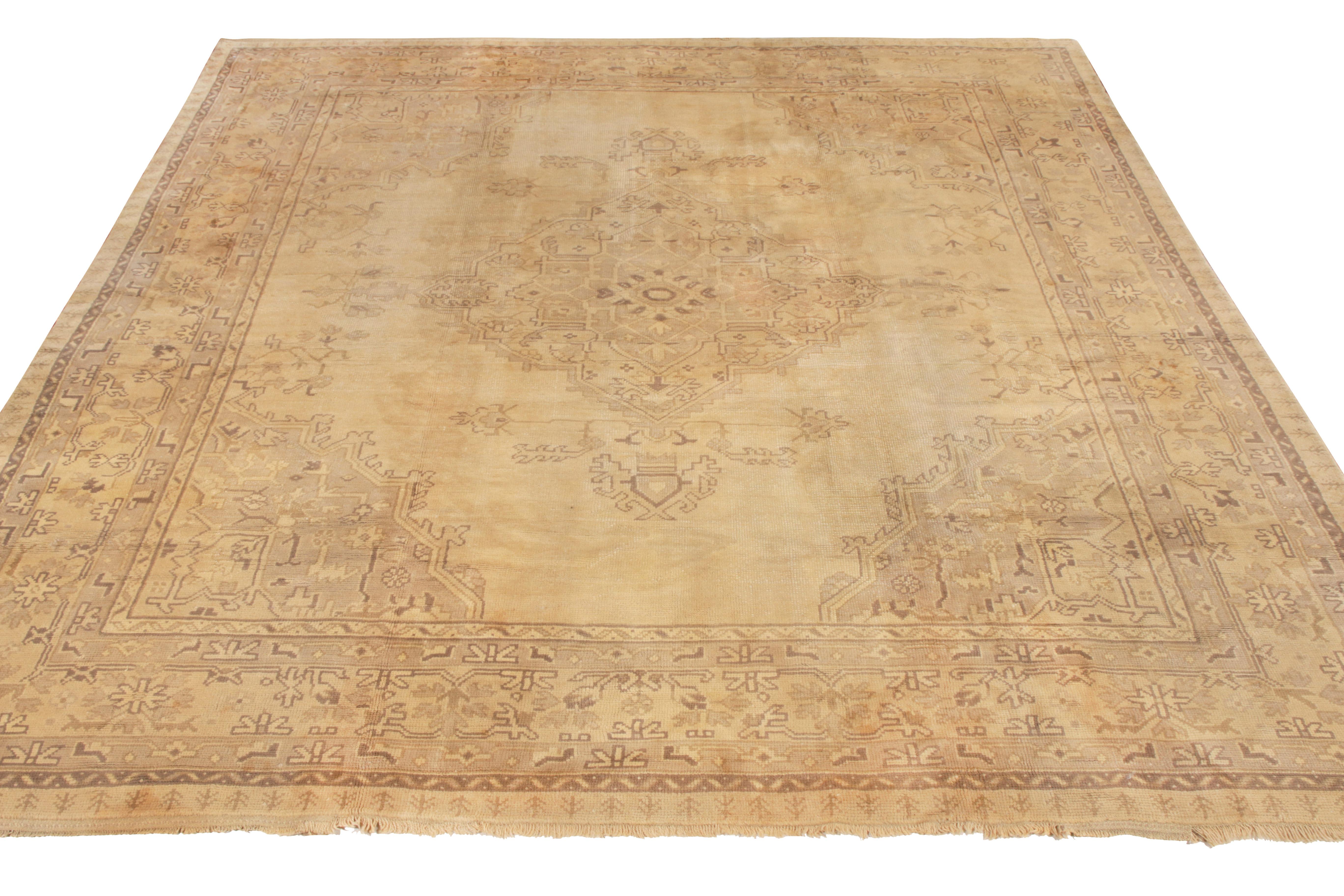 An 11x12 vintage rug celebrating the Oushak style, hand knotted in wool originating from Turkey circa 1950–1960. The medallion style geometric pattern enjoys a subtle, uncommon gray accent to the beige-brown palette that effortlessly complements the