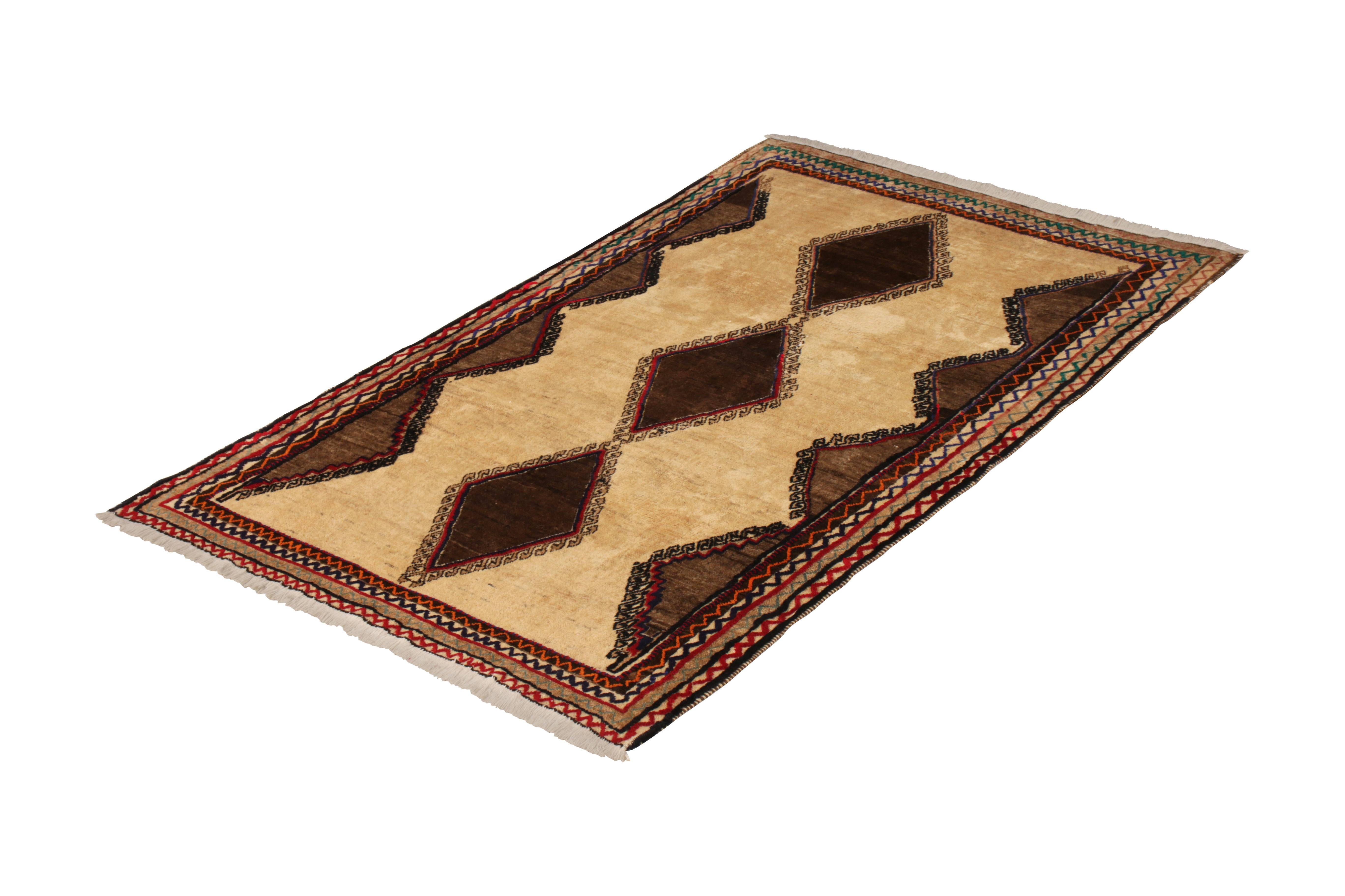 A 5 x 8 vintage Persian rug of Gabbeh tribal design, hand-knotted in wool originating, circa 1950-1960. Warm and rich beige-brown hues with colorful accents among classic mid-century Gabbeh diamond patterns and meandering borders. In good condition