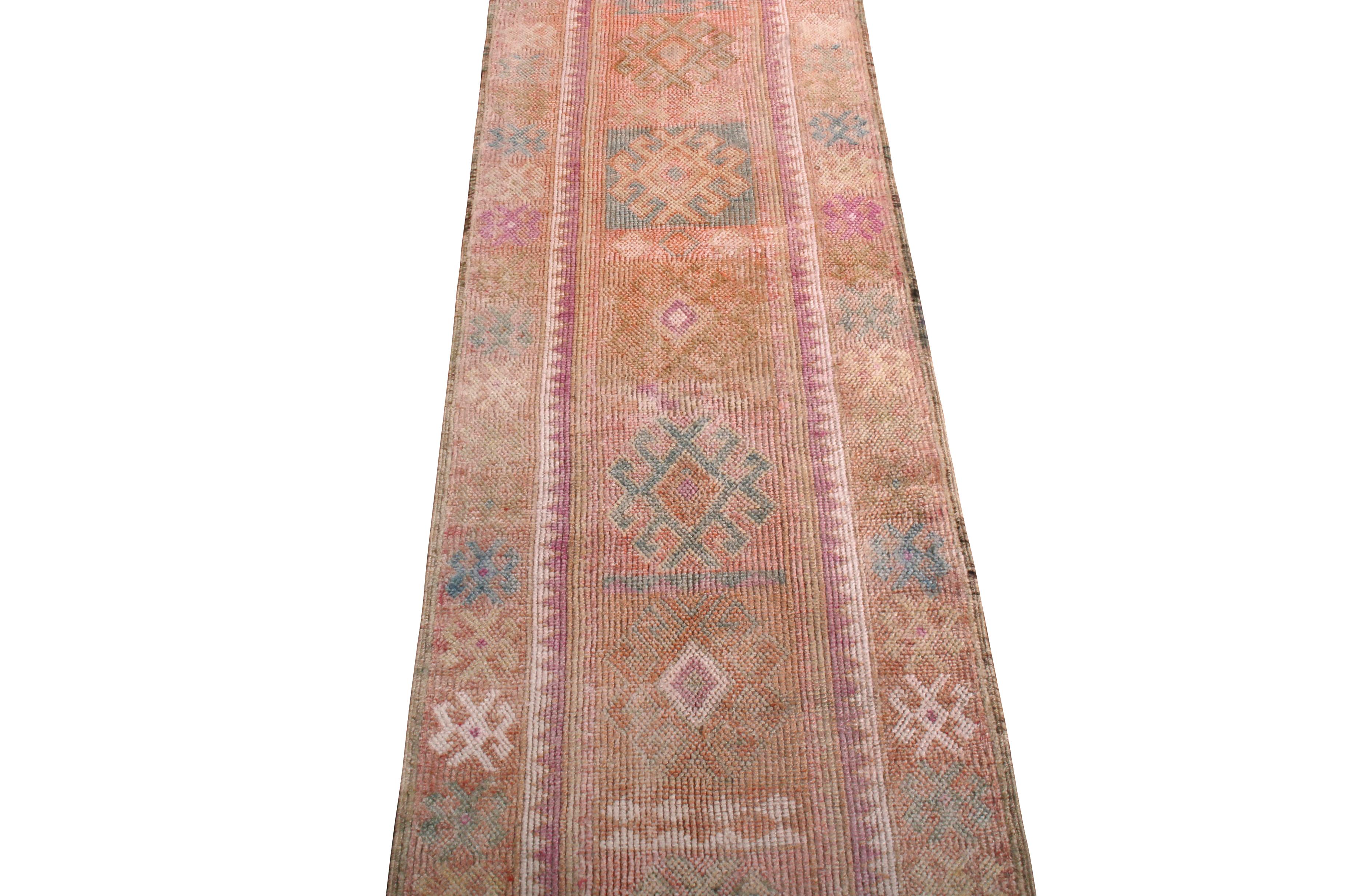 Hand knotted in wool originating from Turkey circa 1950-1960, this 3 x 12 runner connotes a vintage tribal rug design of notable size, a textural weave, and a distinctive warm colorway—playing orange and pink hues against beige brown in a lively,